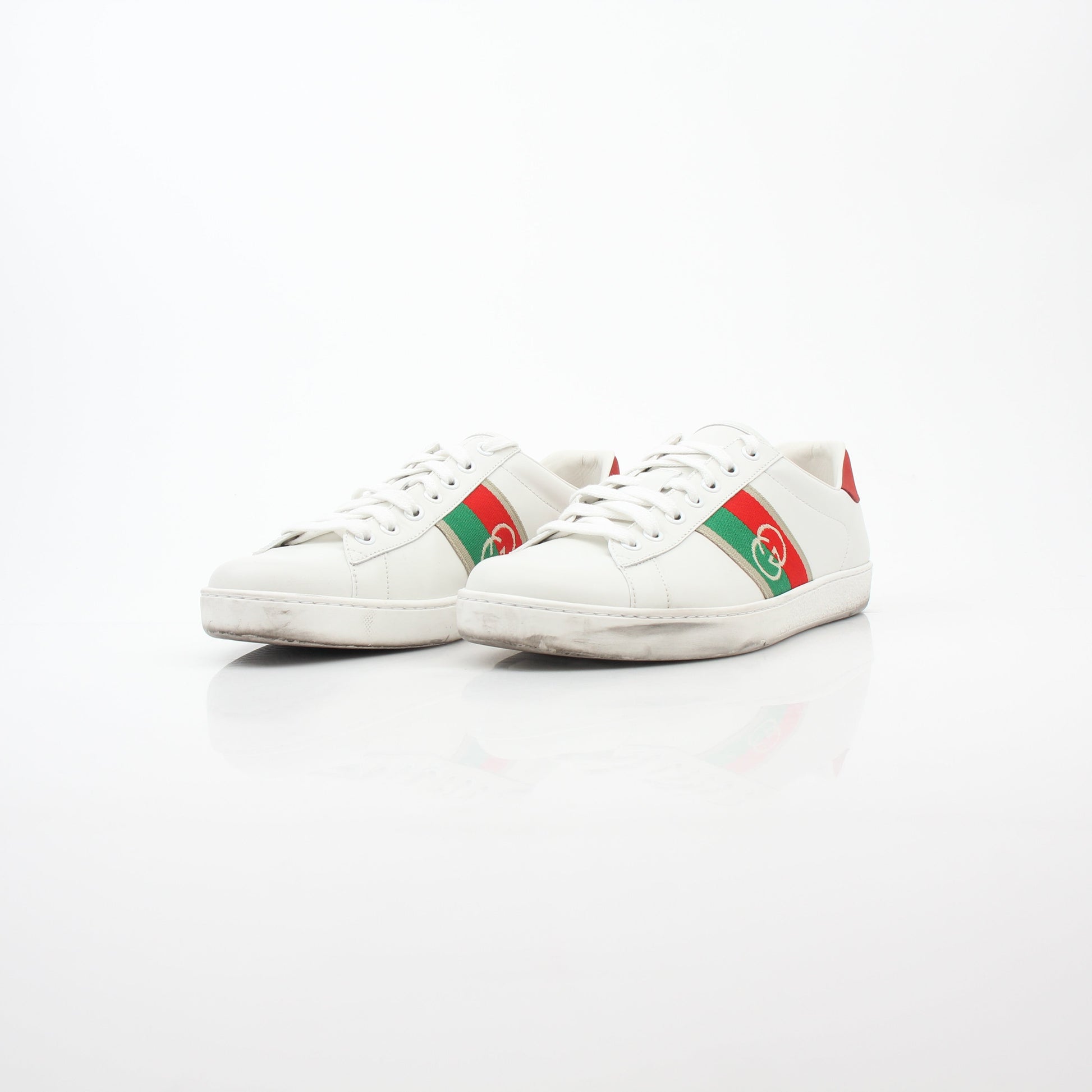 White Gucci Ace sneakers with interlocking G web leather detail, featuring classic design and brand logo on the side.