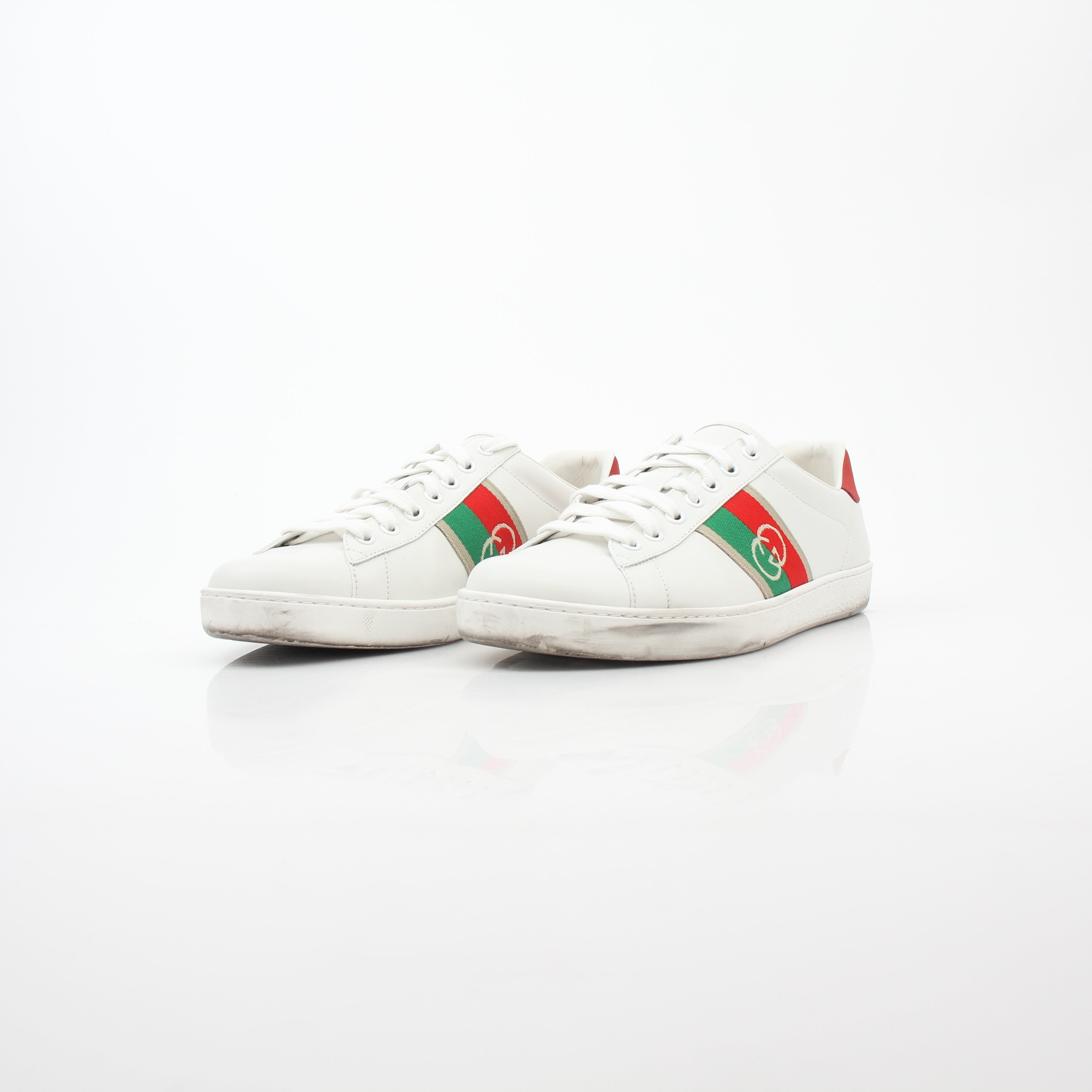 White Gucci Ace sneakers with interlocking G web leather detail, featuring classic design and brand logo on the side.