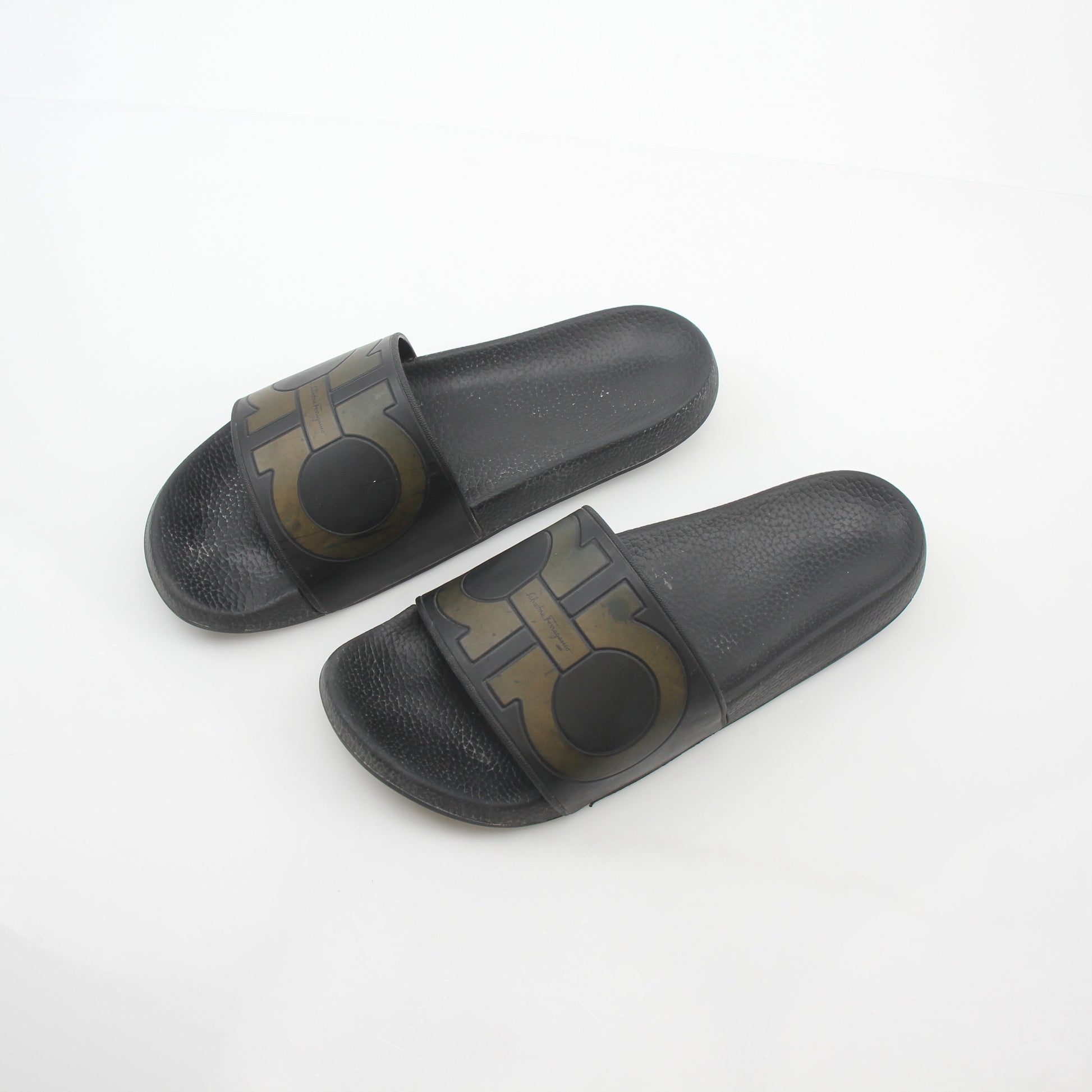 Black Salvatore Ferragamo Groove 2 Gancini slide sandals with leather straps and Gancini hardware, worn on a model's feet.