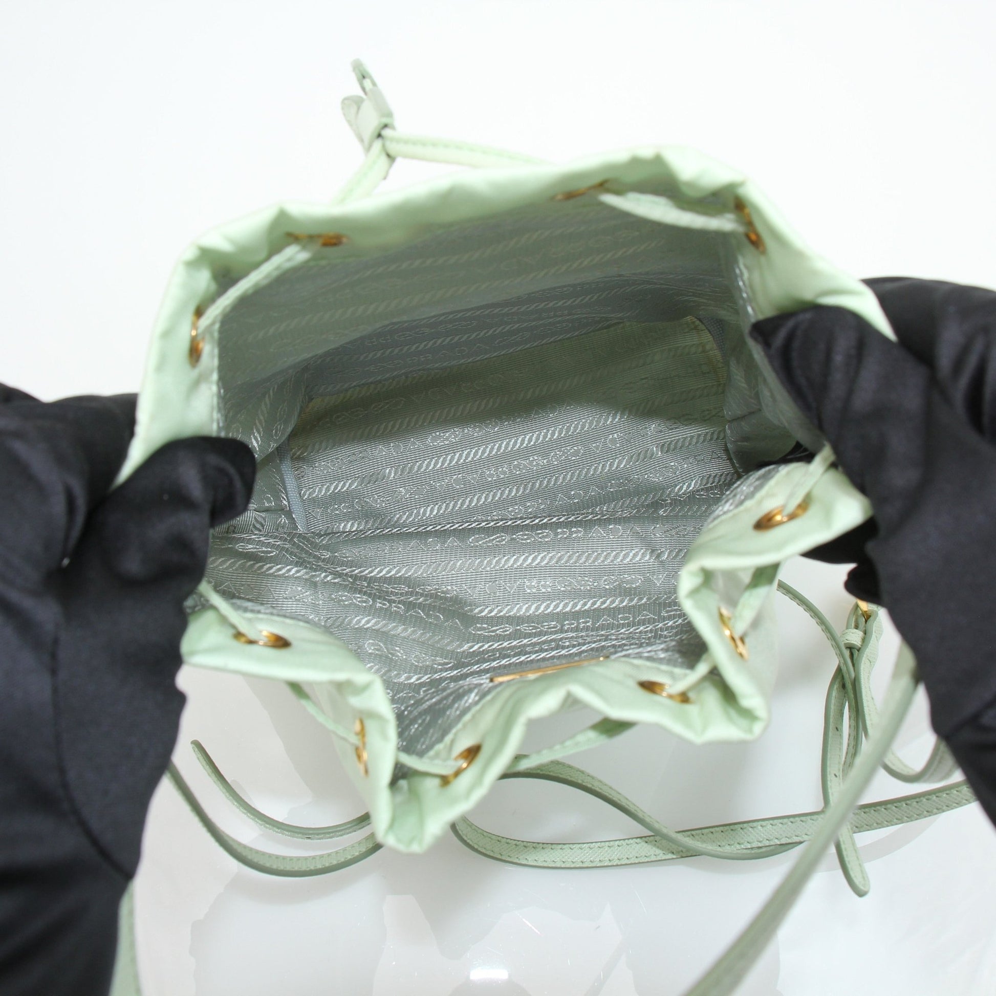 Prada nylon drawstring handbag with adjustable straps and sleek design, featuring the Prada logo on the front.