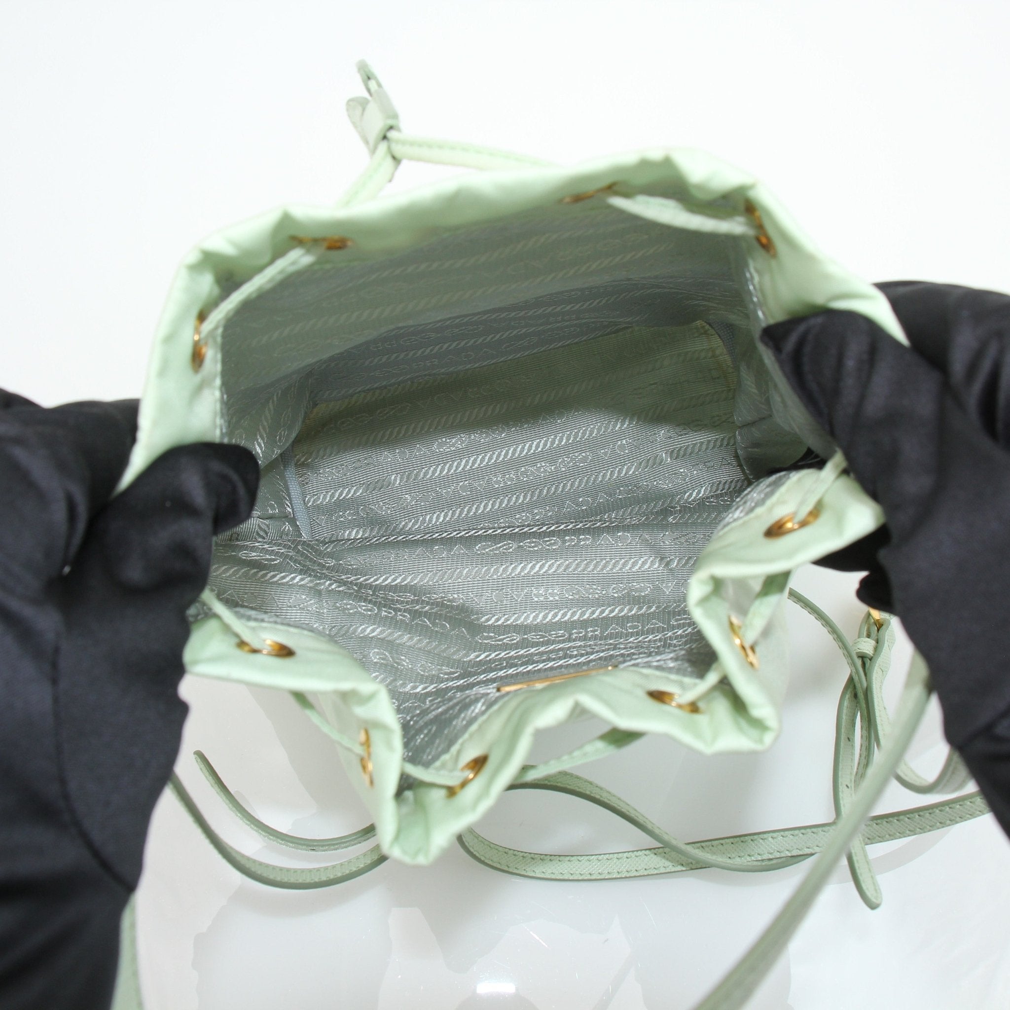 Prada nylon drawstring handbag with adjustable straps and sleek design, featuring the Prada logo on the front.