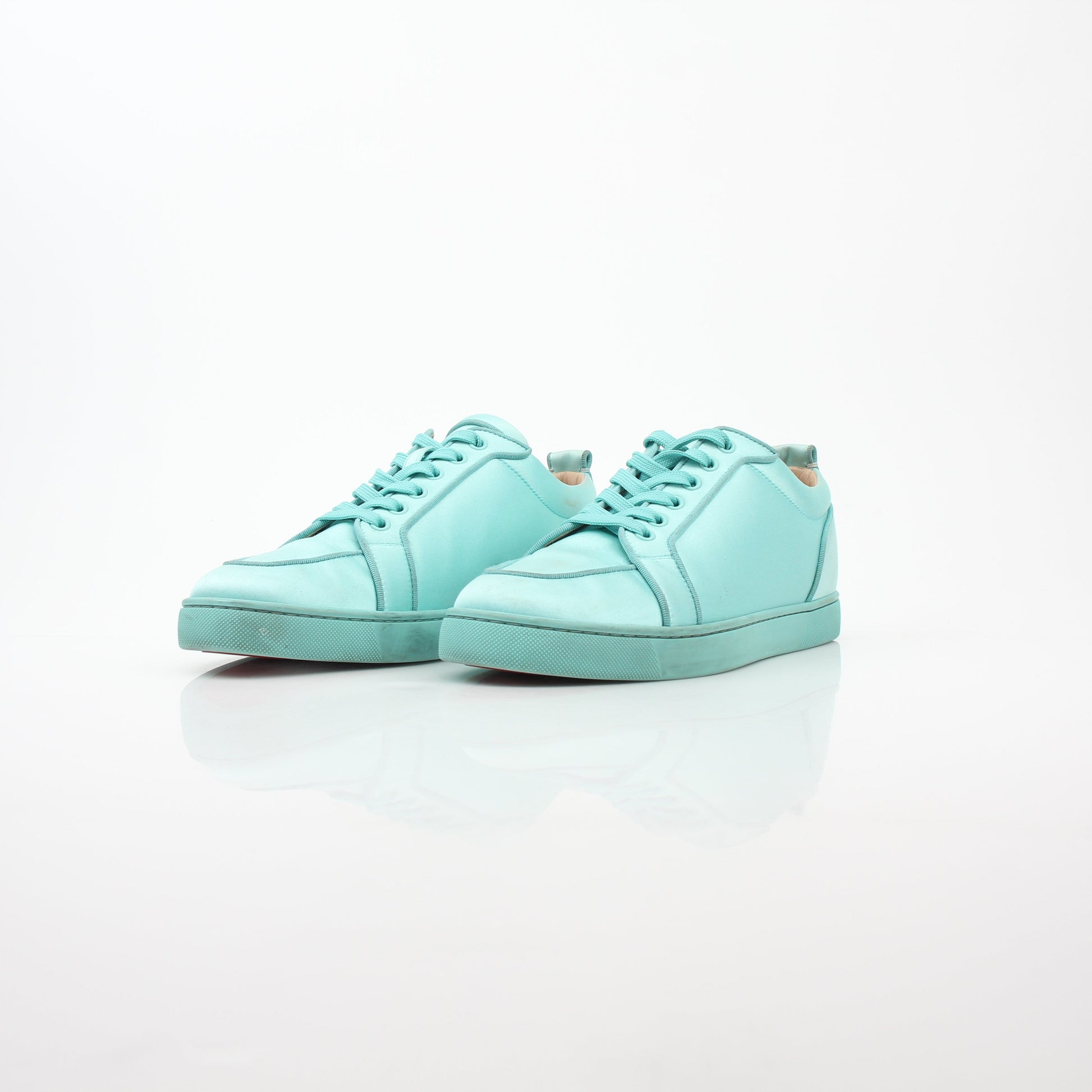Christian Louboutin turquoise Rantulow Orlato low-top sneakers with gold accents and signature red soles, displayed on a white background.