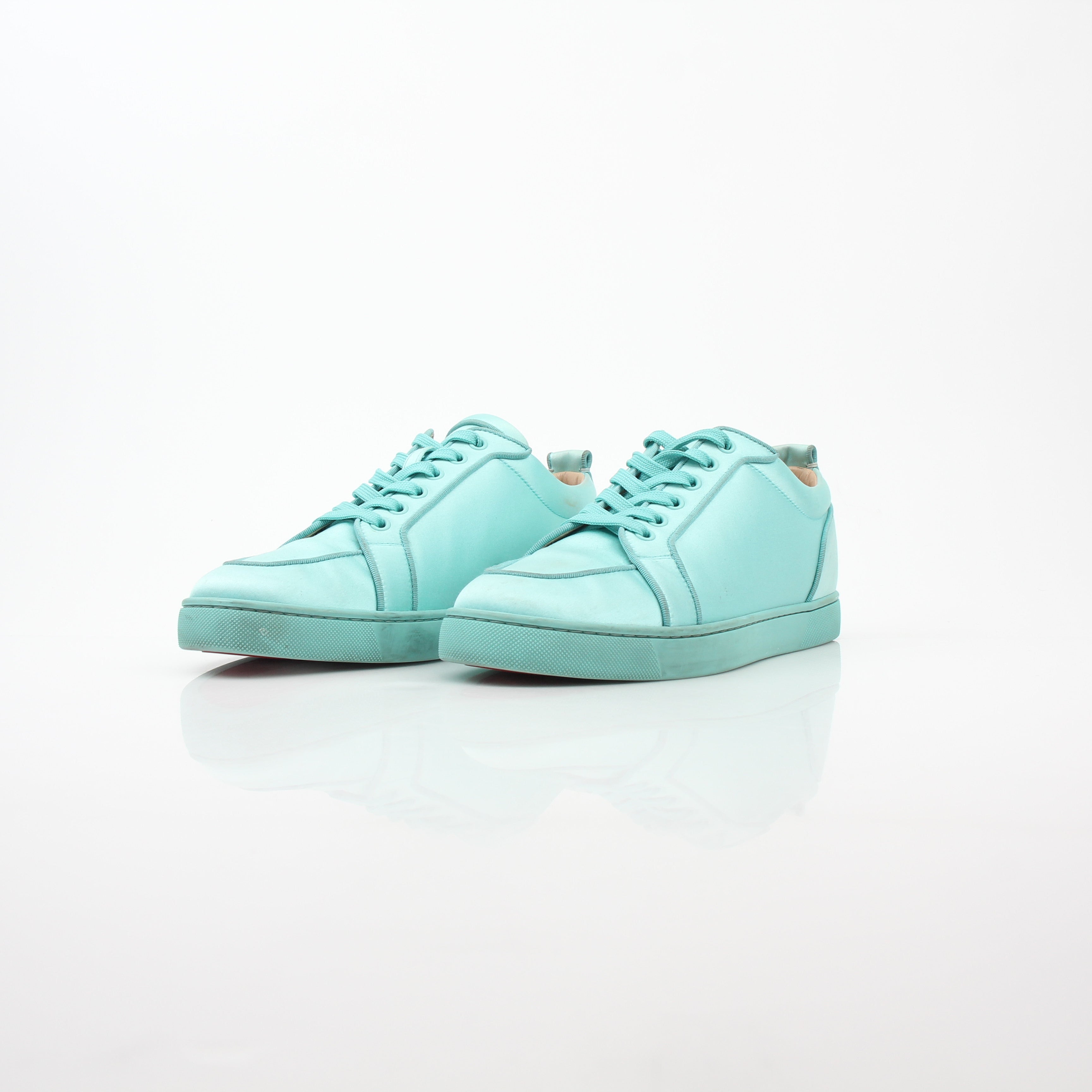 Christian Louboutin turquoise Rantulow Orlato low-top sneakers with gold accents and signature red soles, displayed on a white background.