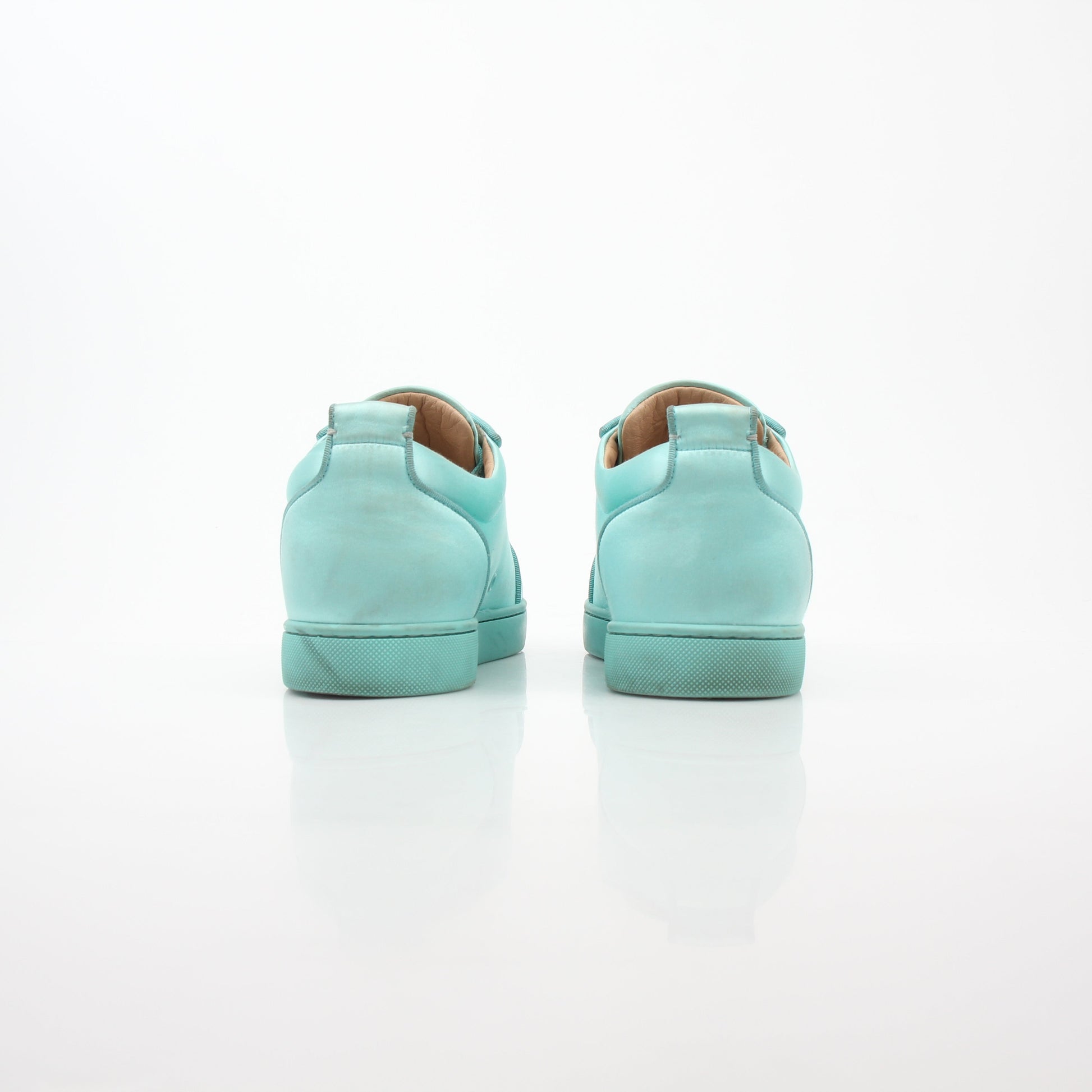 Christian Louboutin turquoise Rantulow Orlato low-top sneakers with textured leather and signature red sole, displayed on a white background.