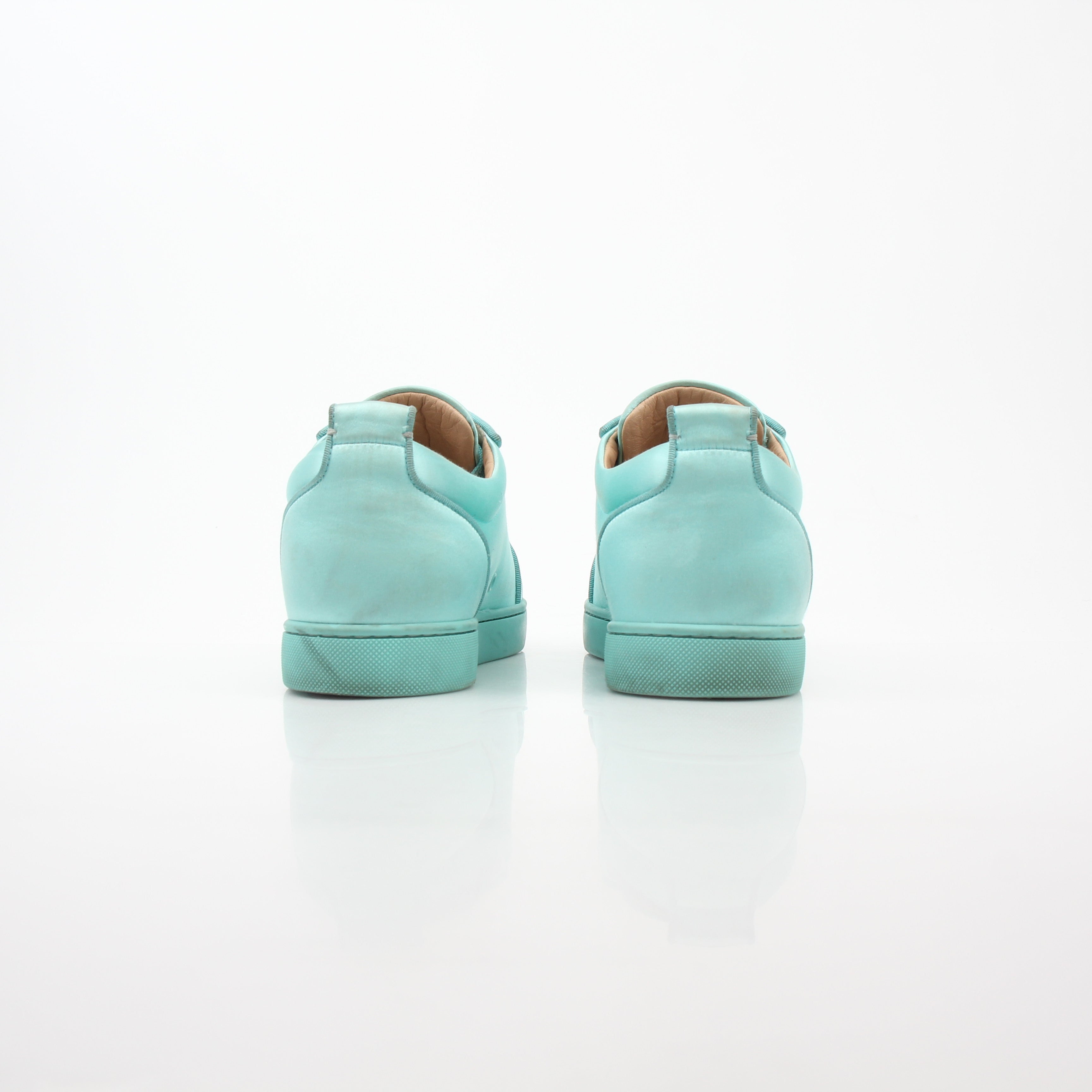 Christian Louboutin turquoise Rantulow Orlato low-top sneakers with textured leather and signature red sole, displayed on a white background.