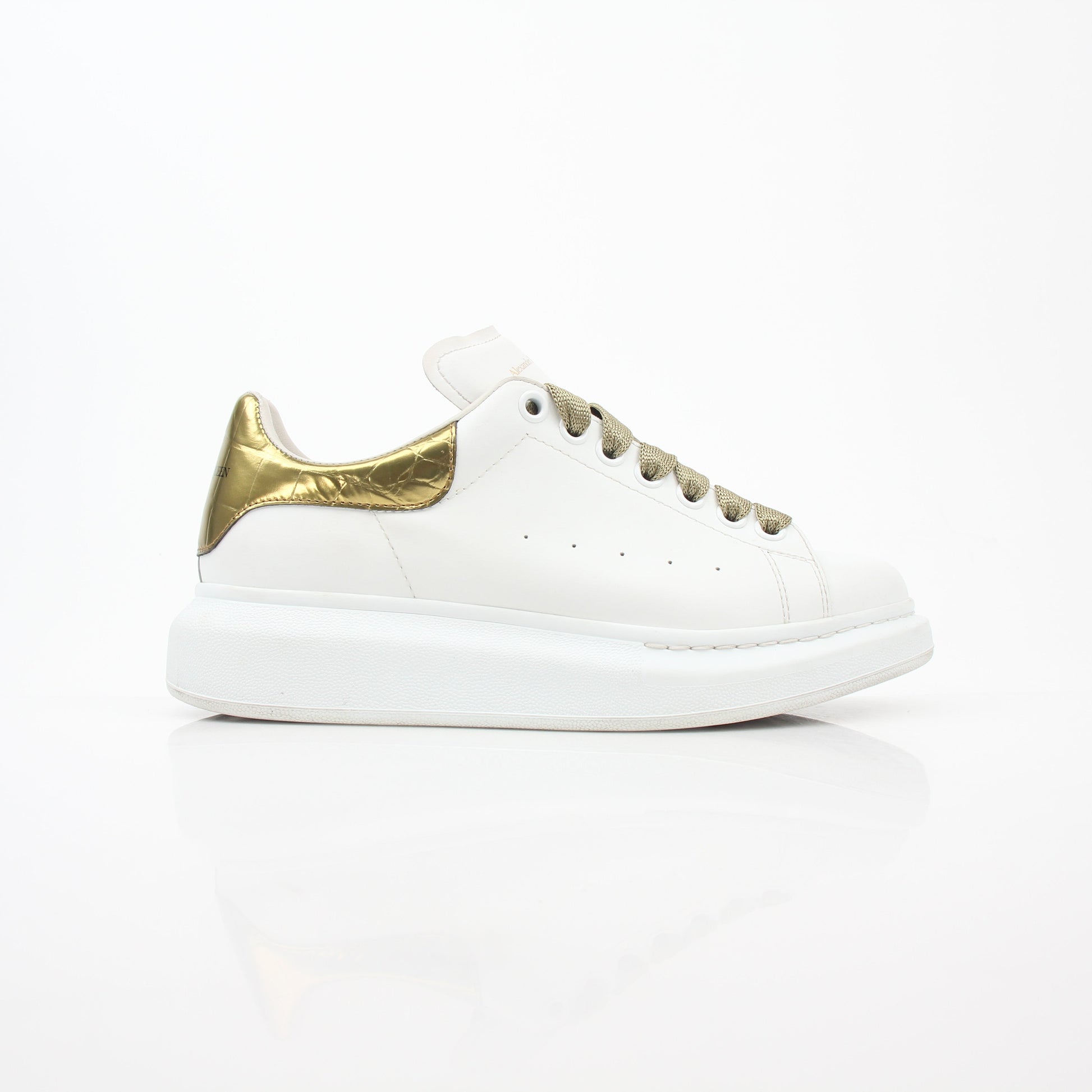 Alexander McQueen white gold oversized low-top sneakers, stylish shoes with a chunky sole and metallic accents.