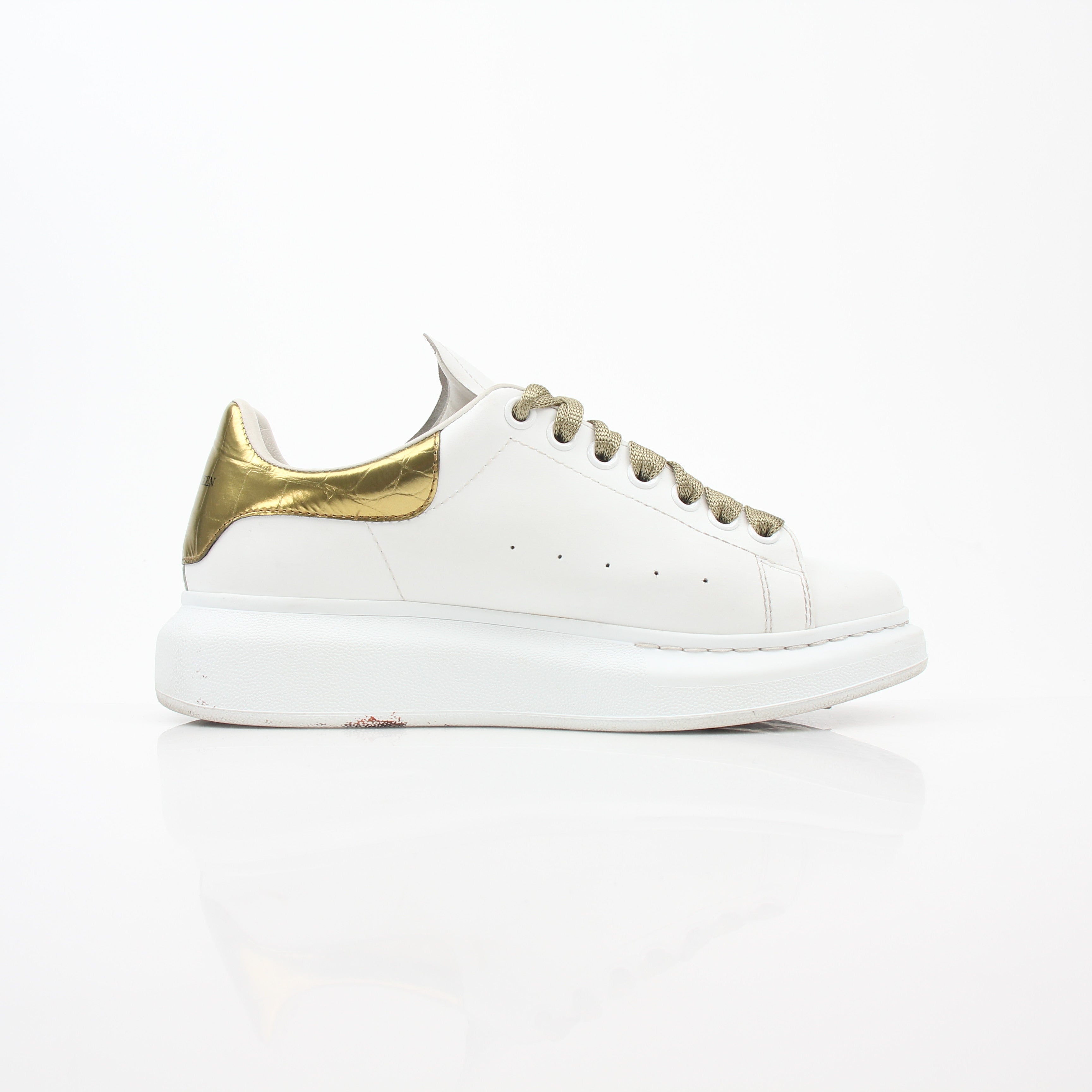 Alexander McQueen white gold oversized low-top sneakers by Gold & Beyond, showing the stylish shoes with white and gold accents.