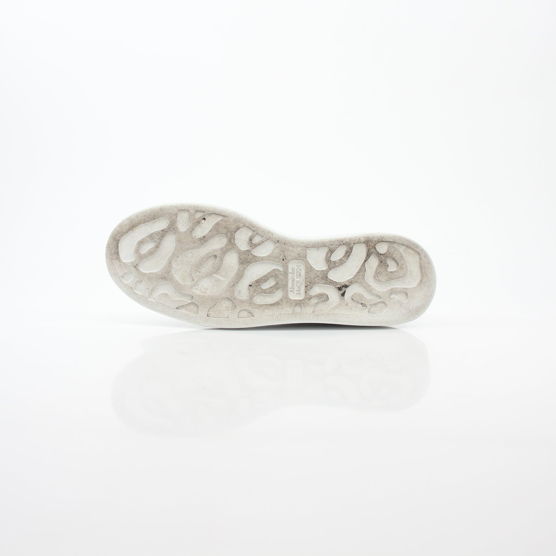 Alexander McQueen white gold oversized low-top sneakers, stylish shoes featuring sleek design and chunky soles, worn casually.
