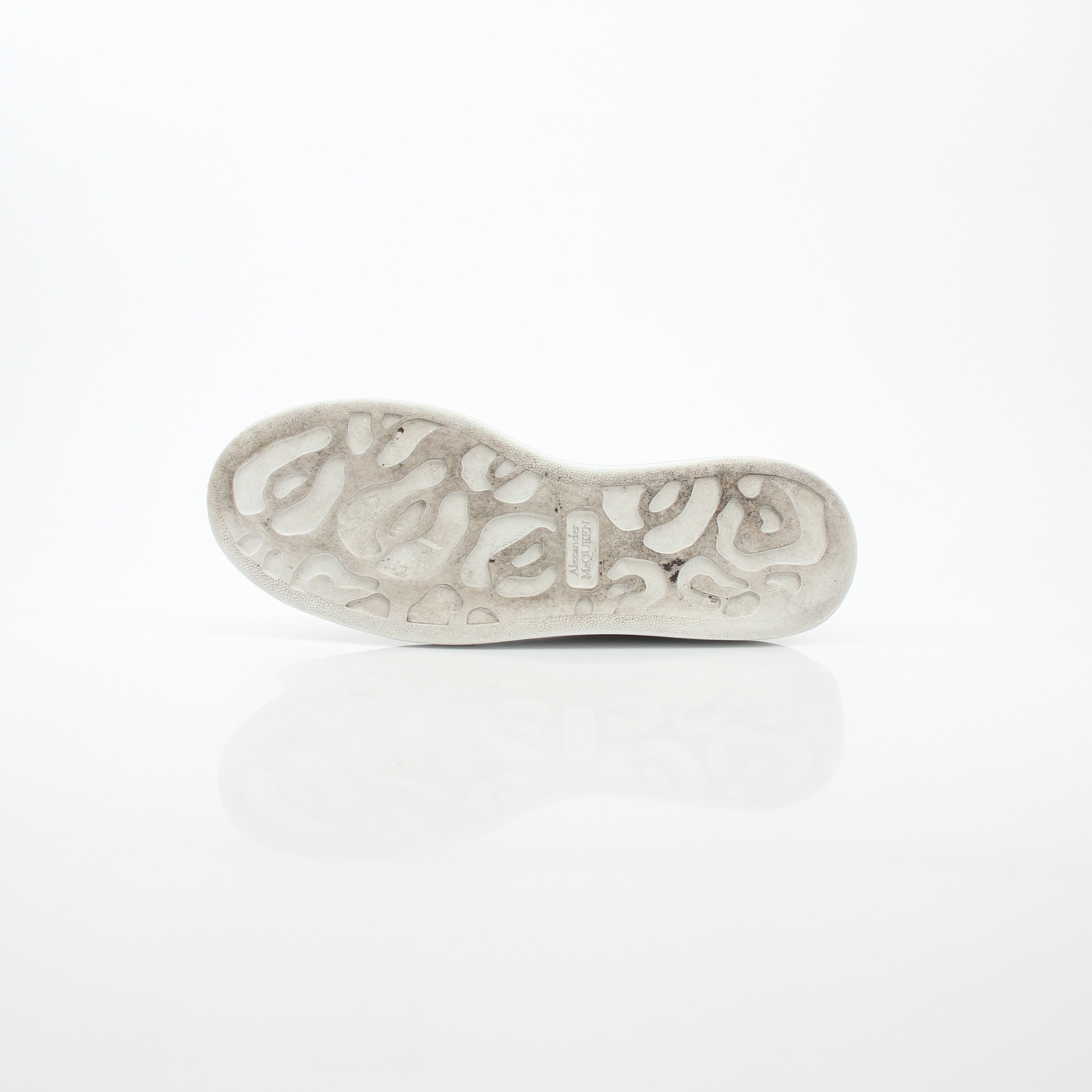 Alexander McQueen white gold oversized low-top sneakers, stylish shoes featuring sleek design and chunky soles, worn casually.