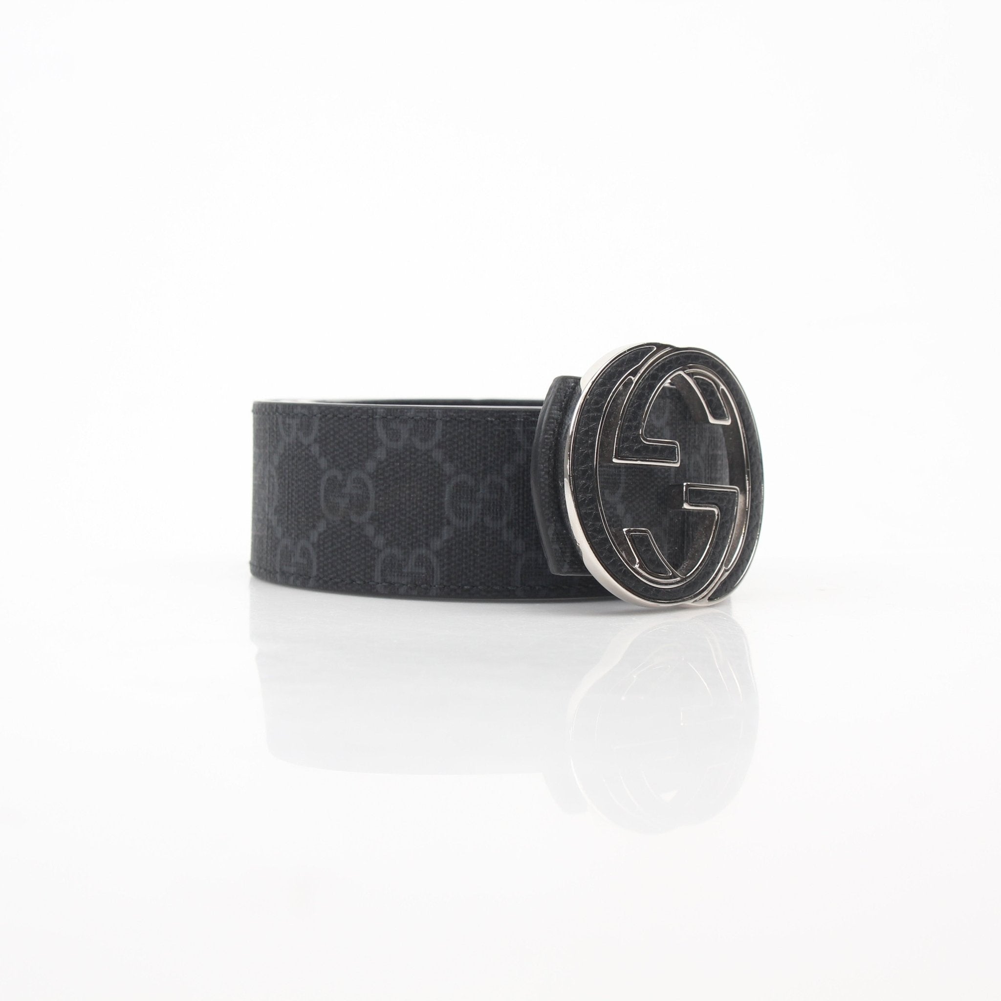 Gucci black GG Supreme reversible belt with interlocking G design, shown with gold-tone buckle and leather strap.