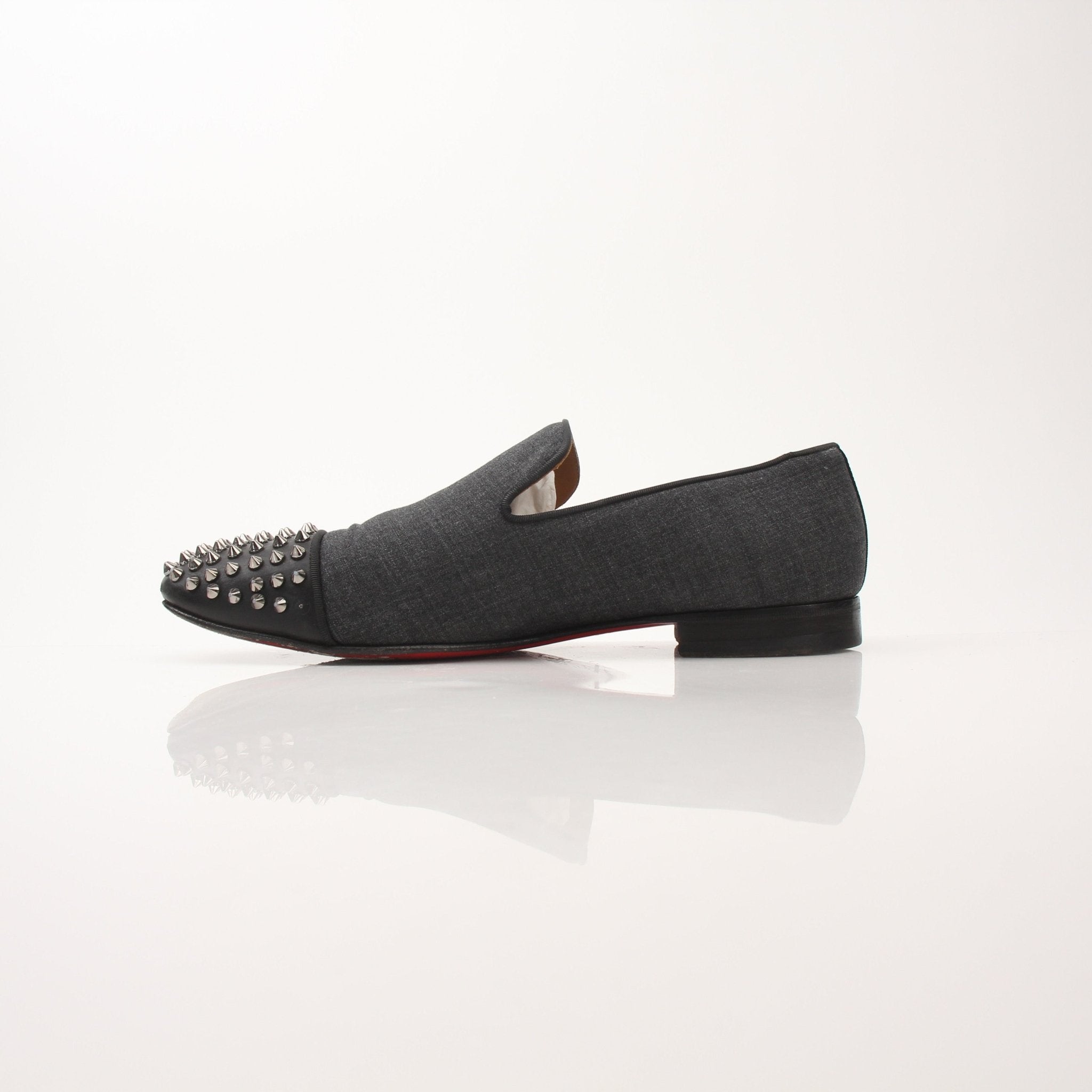 Christian Louboutin men's Spooky Spike flat loafers with black leather and distinctive spike detailing, worn on a stylish shoe display.