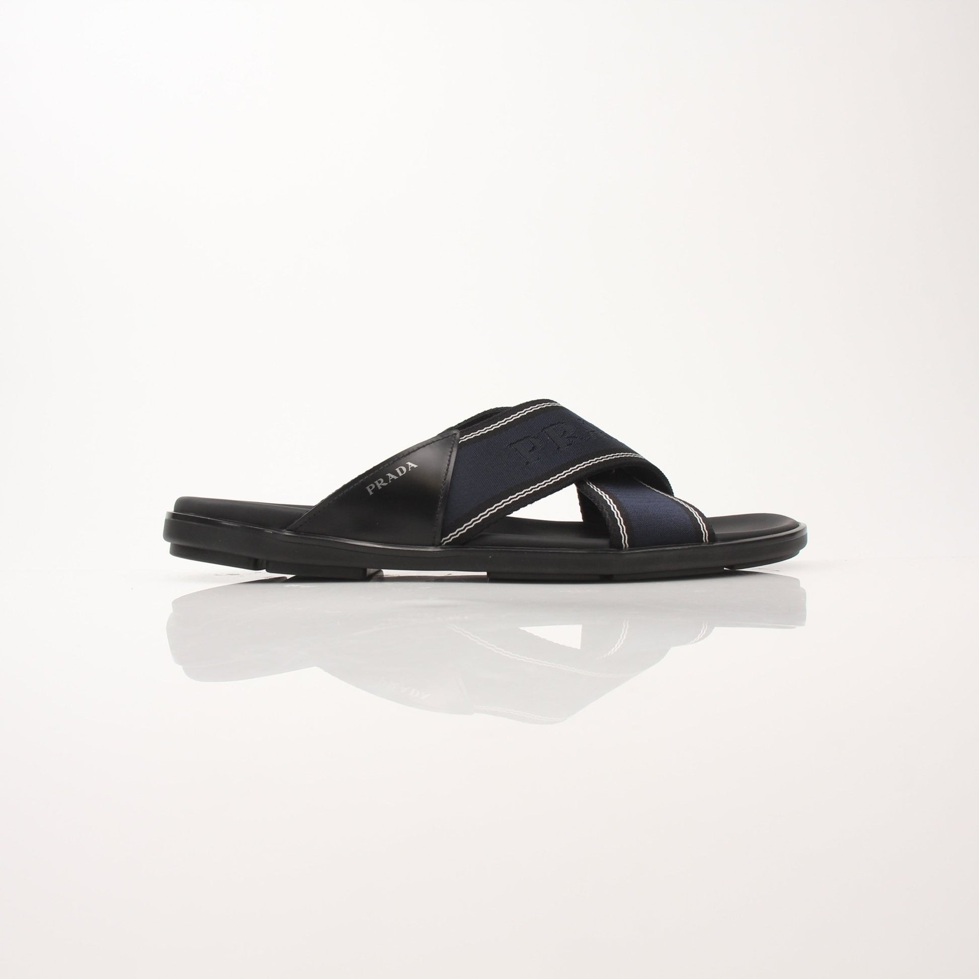 Prada men's leather and Re-Nylon sandals, black and beige, with open-toe design and adjustable straps, on a neutral background.