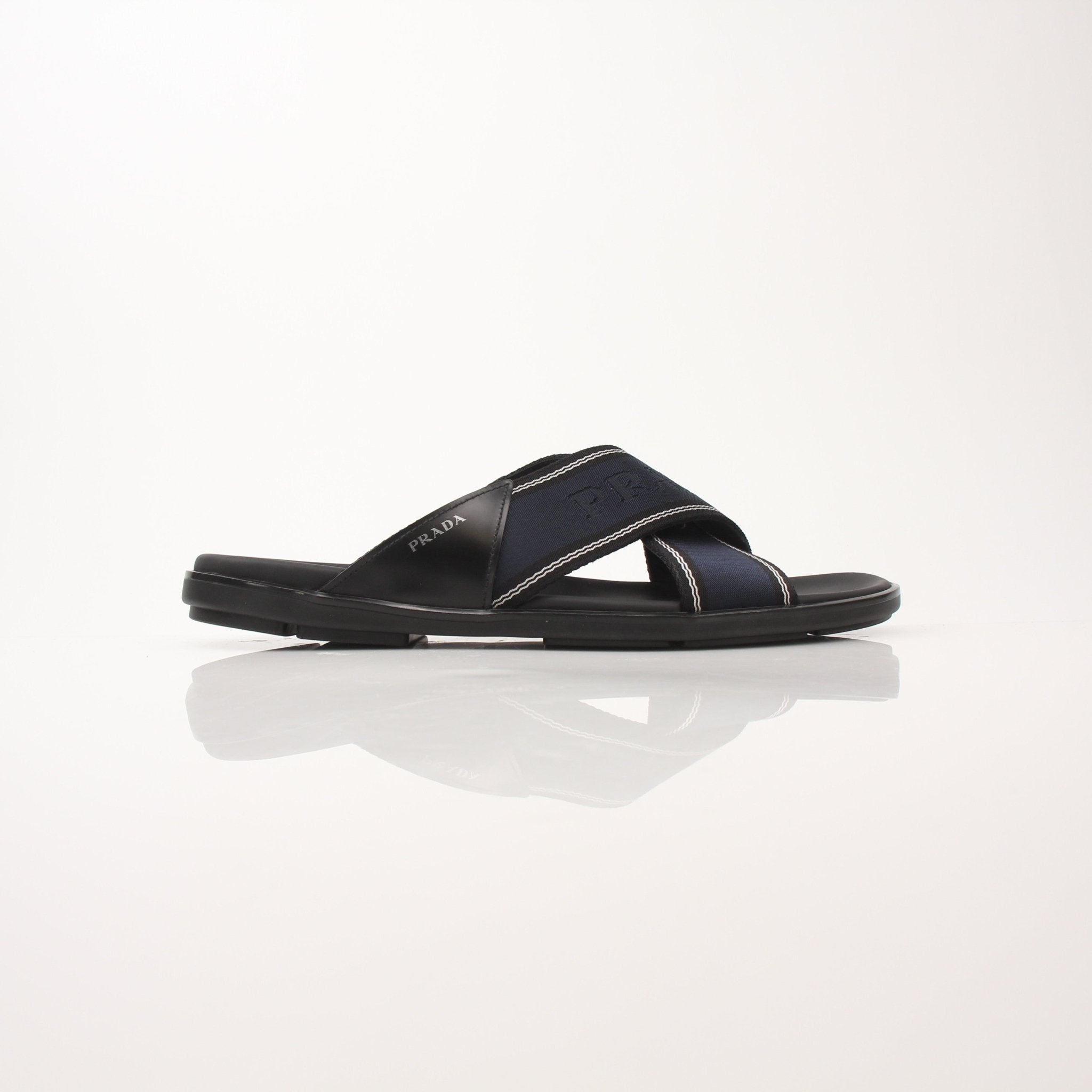 Prada men's leather and Re-Nylon sandals, black and beige, with open-toe design and adjustable straps, on a neutral background.