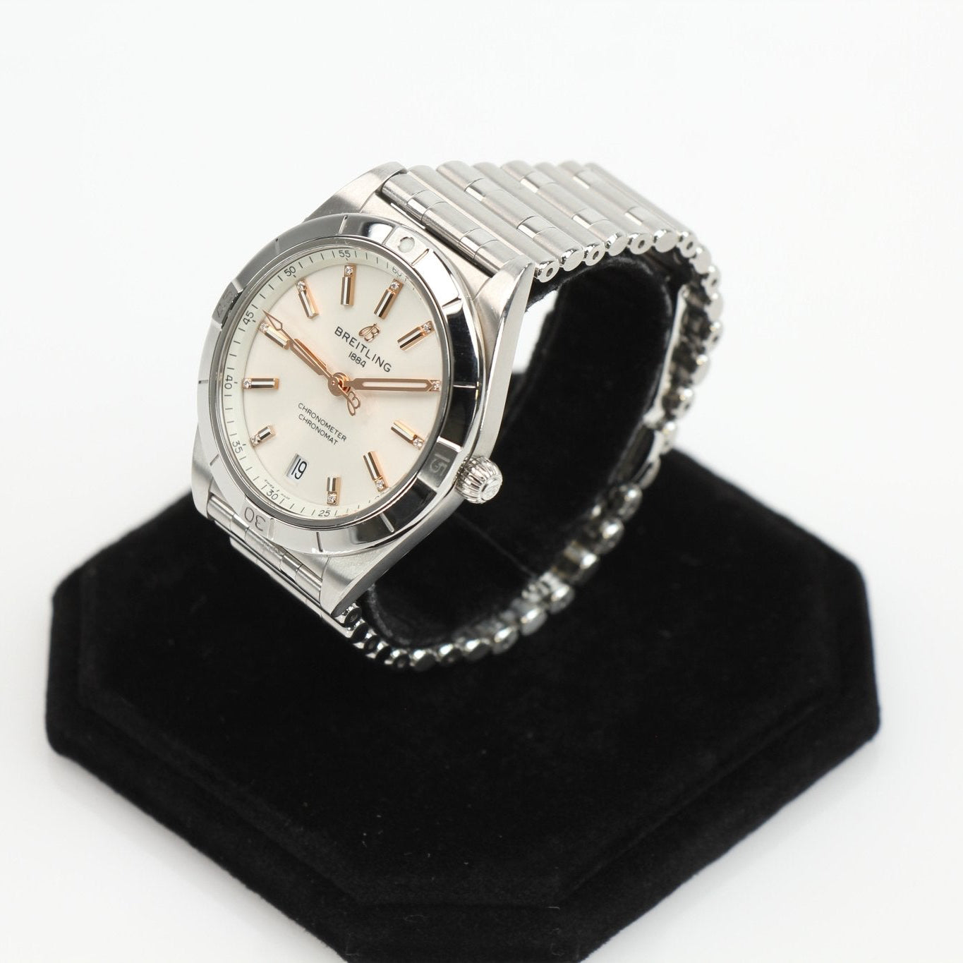 Stainless steel Breitling Chronomat watch with detailed dial and chronograph features, displayed on a stand.