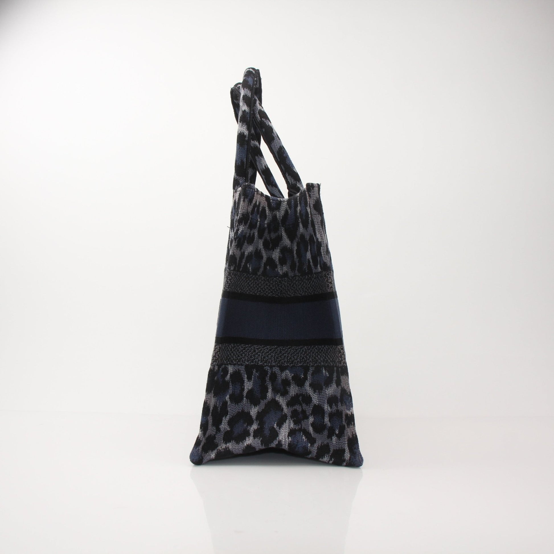 Christian Dior Leopard Book Tote handbag with gold accents, featuring bold leopard print and sturdy handles.