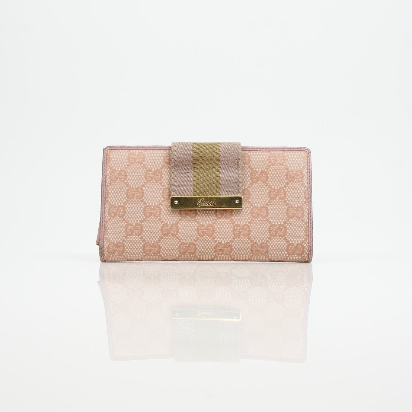 Gucci pink GG Continental wallet with gold accents, leather exterior, and multiple card slots, on a neutral background.