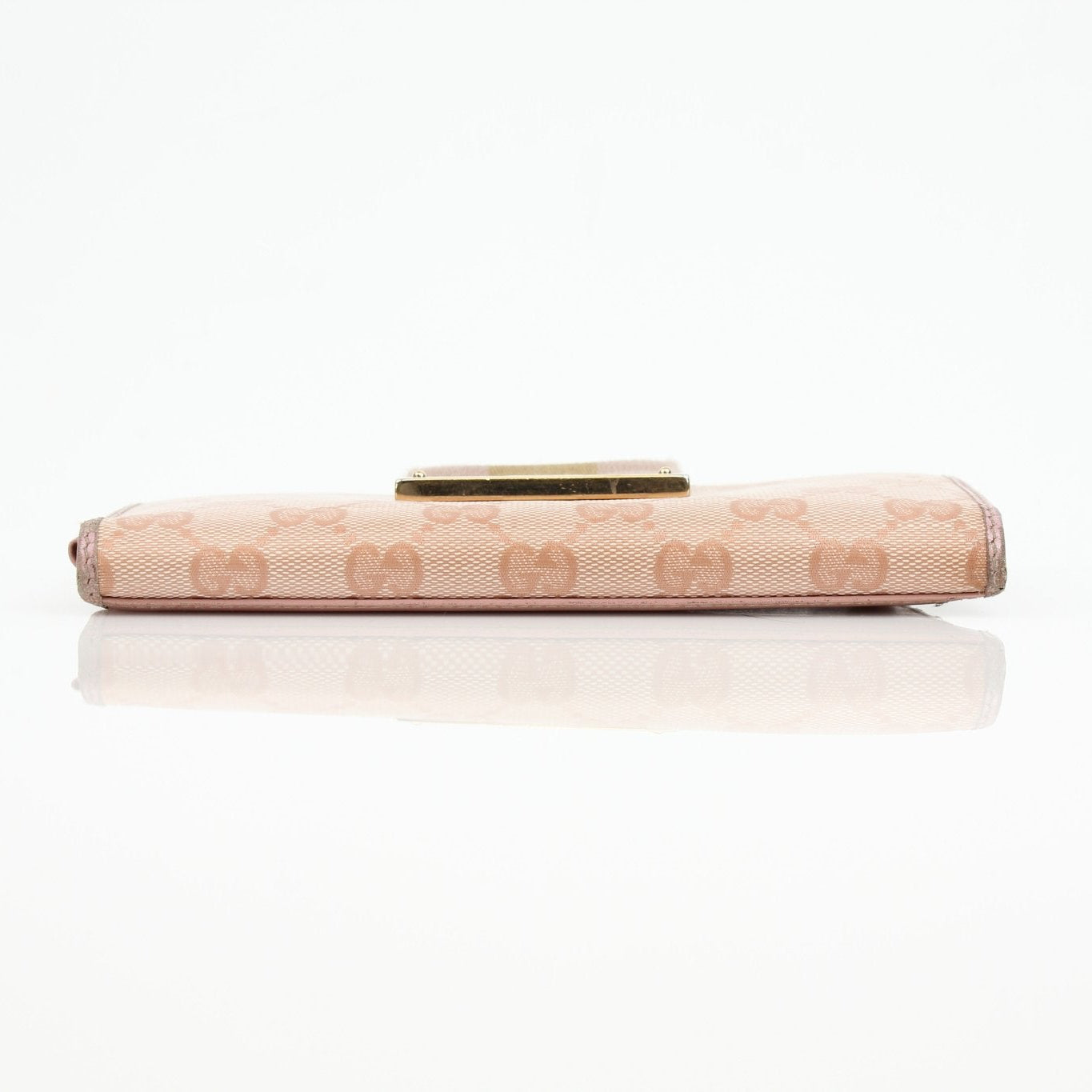 Gucci pink GG continental wallet with gold accents, featuring a compact design and signature monogram pattern.