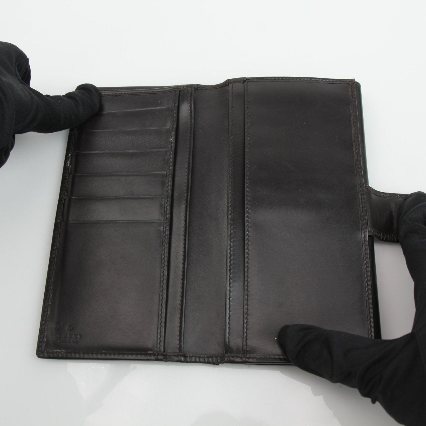 Gucci Guccissima canvas wallet with gold-tone logo and brown leather trim, displayed open showing card slots and cash compartment.