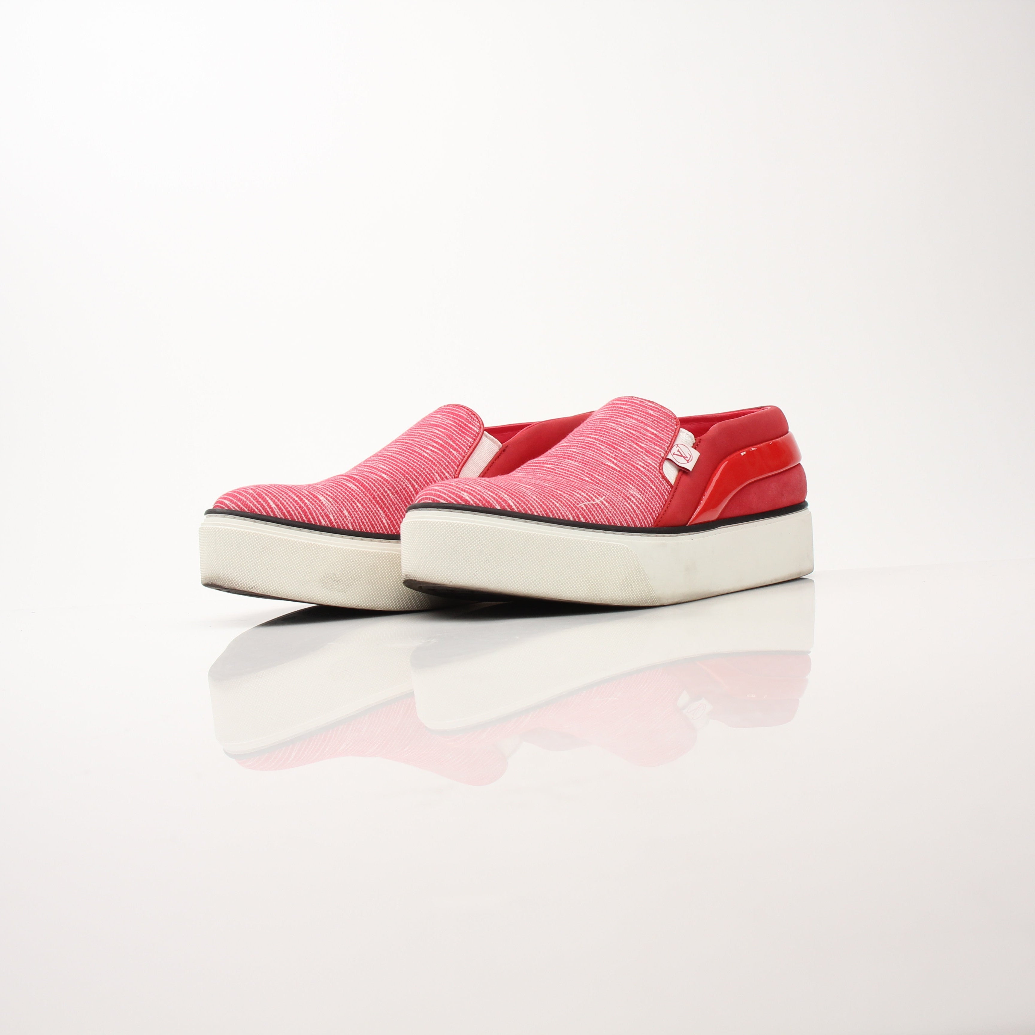 Red Louis Vuitton slip-on sneakers with white soles and gold accents, designed for stylish comfort.