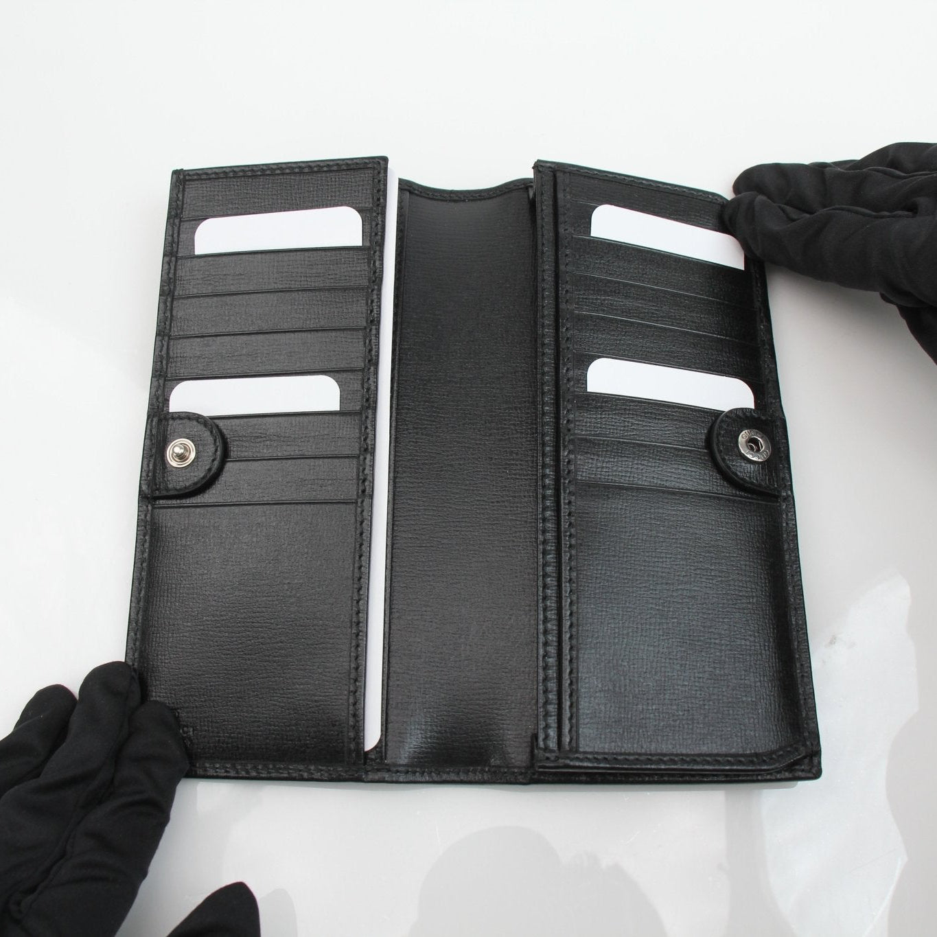 Gucci GG Supreme black wallet with gold accents, featuring a sleek design and multiple card slots, by Gold & Beyond.