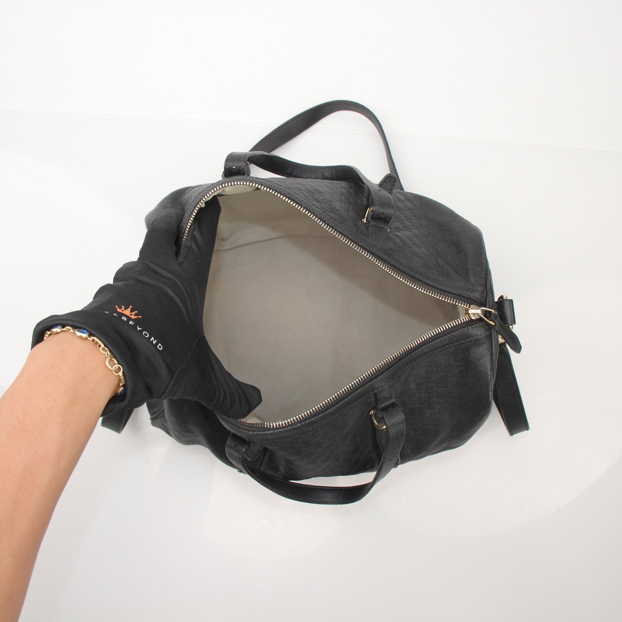 Gucci black Joy Boston handbag with gold accents, showing the structured shape and top handles against a neutral background.