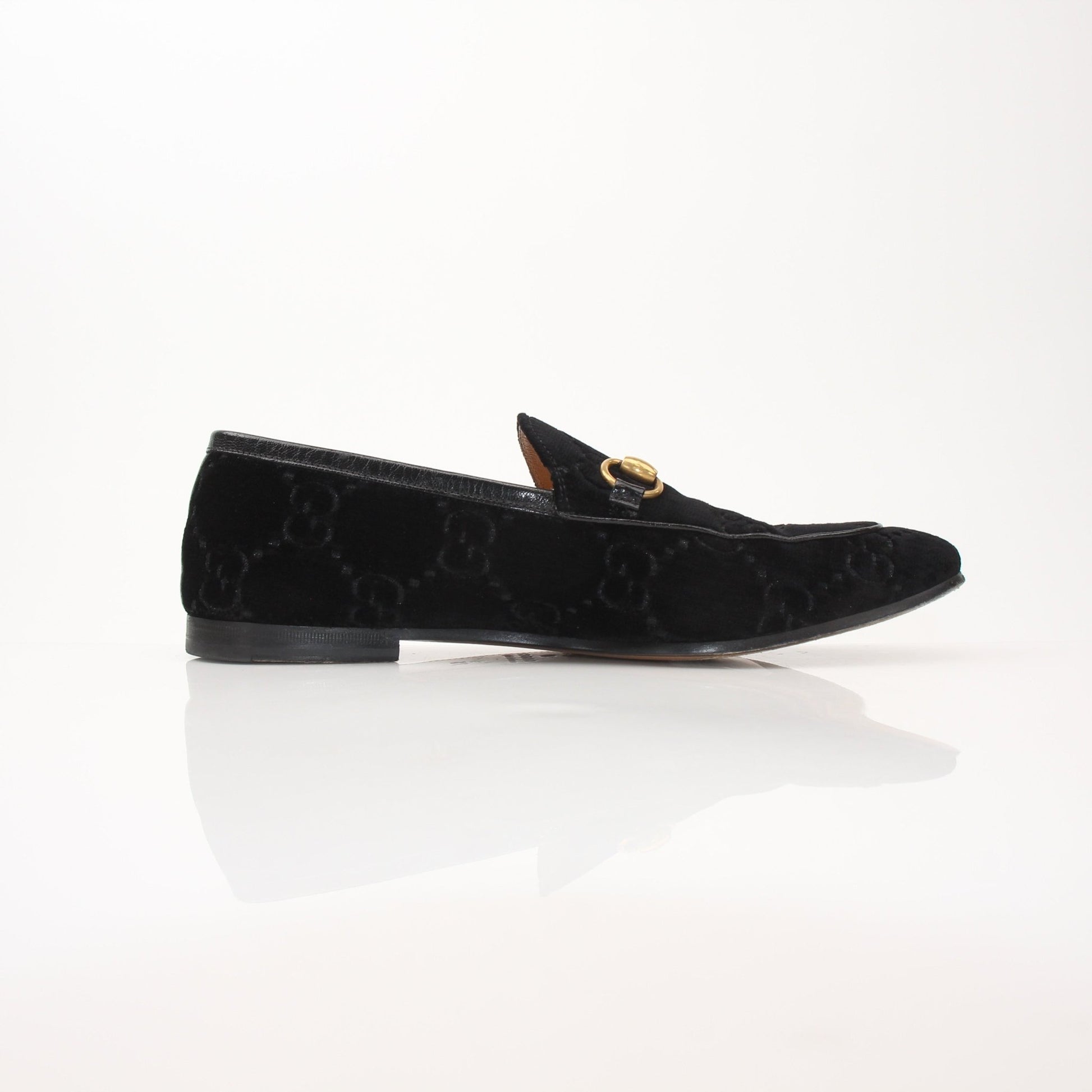 Gucci Men’s Jordaan GG black velvet loafers with gold accents, featuring classic slip-on design and sleek silhouette.