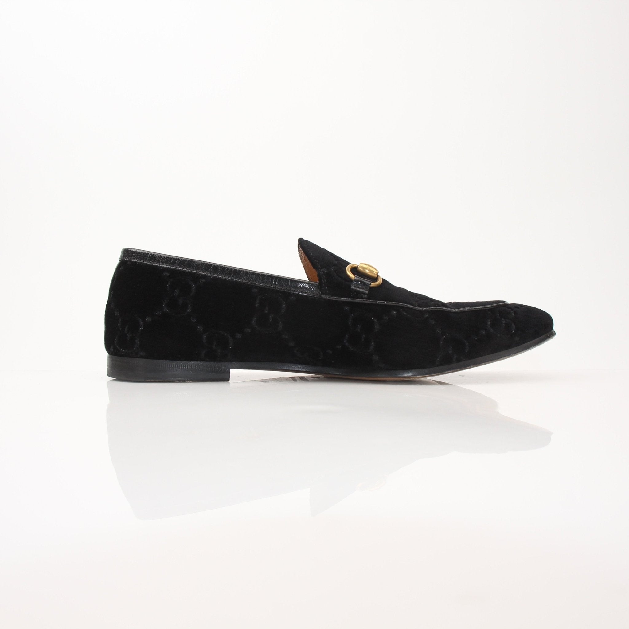 Gucci Men’s Jordaan GG black velvet loafers with gold accents, featuring classic slip-on design and sleek silhouette.