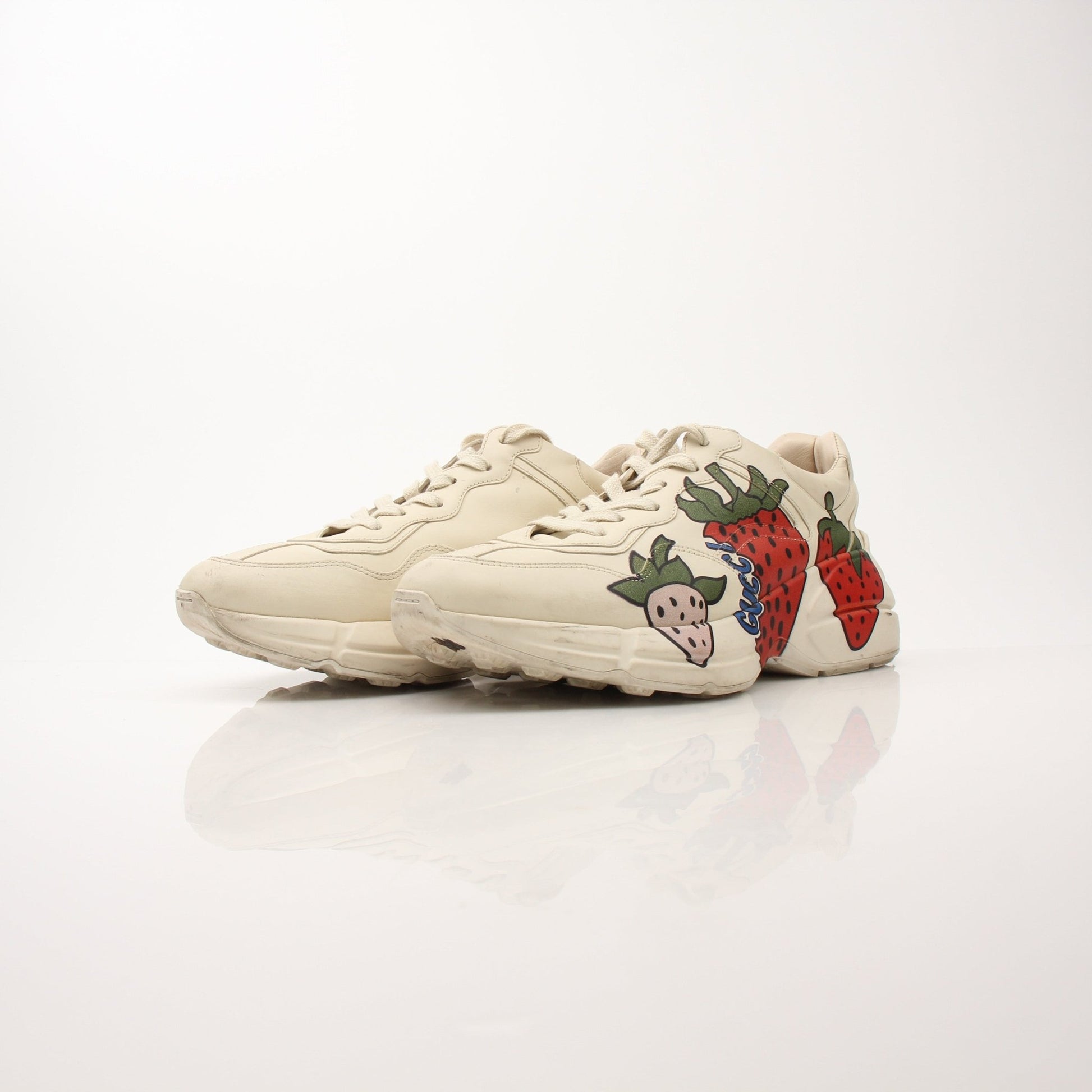 Gucci Women’s Rhyton Strawberry Sneakers featuring white leather with red strawberry embroidery and chunky sole.