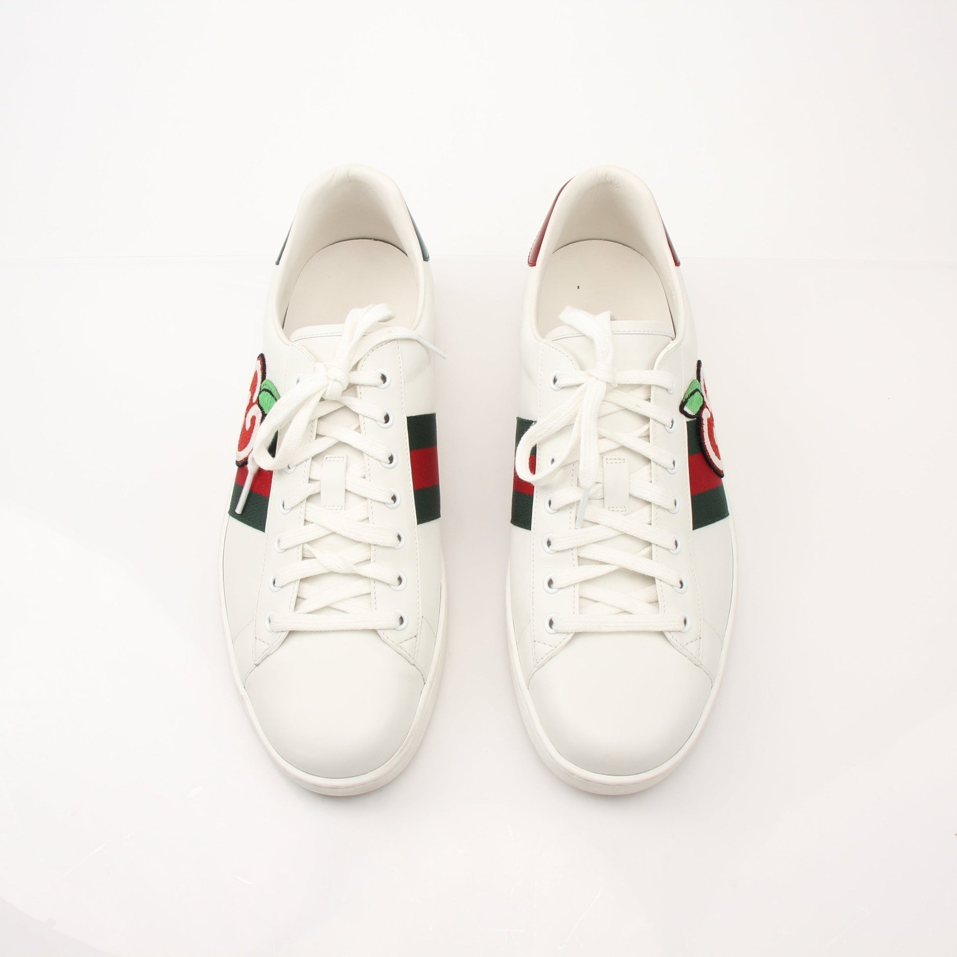 Gold & Beyond Gucci Men’s GG Apple Sneakers featuring stylish design, white soles, and signature GG logo on a sleek shoes display.