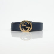 Gucci navy interlocking GG belt with gold hardware, stylish accessory for men and women, displayed on a neutral background.