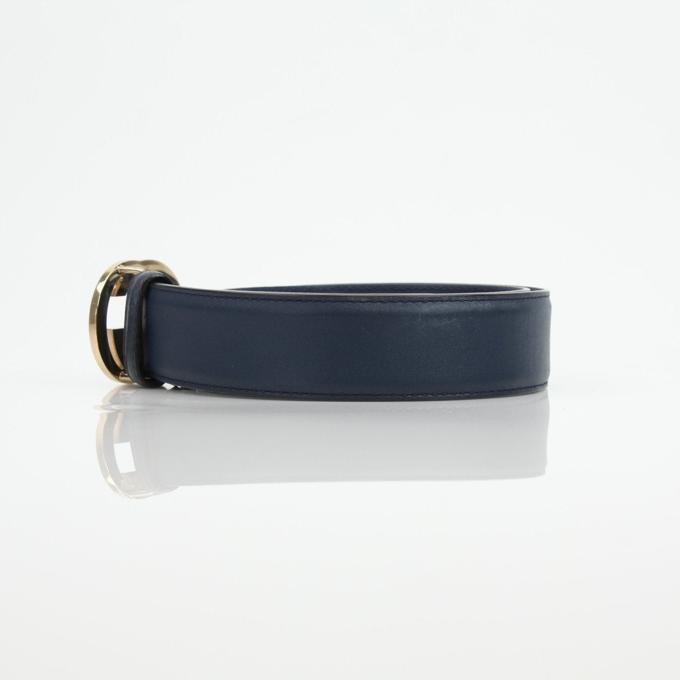 Navy Gucci Interlocking GG belt with gold buckle, stylish accessories displayed on a white background.
