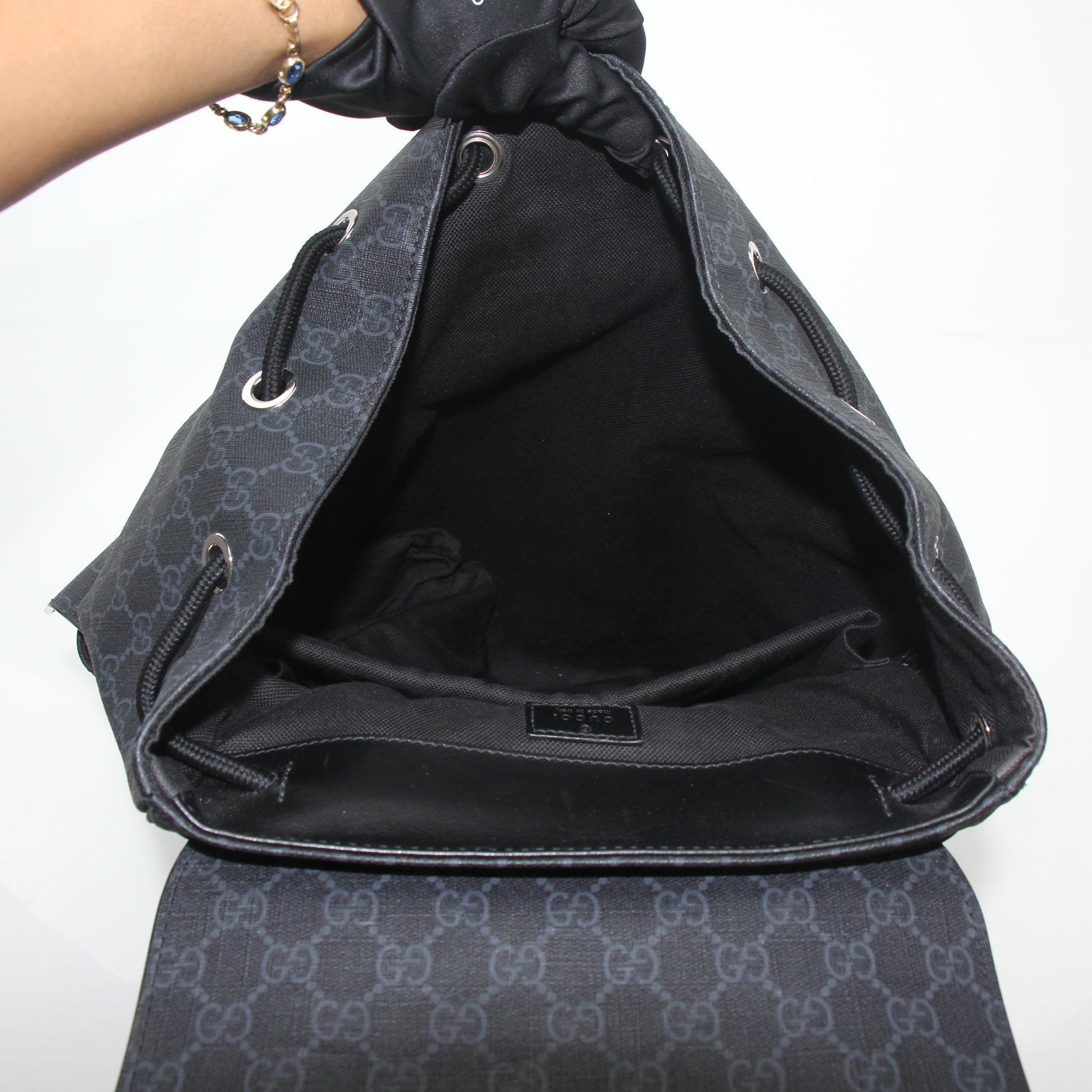 Gucci black GG Supreme Lark backpack, a stylish travel bag with sturdy straps and signature monogram pattern.