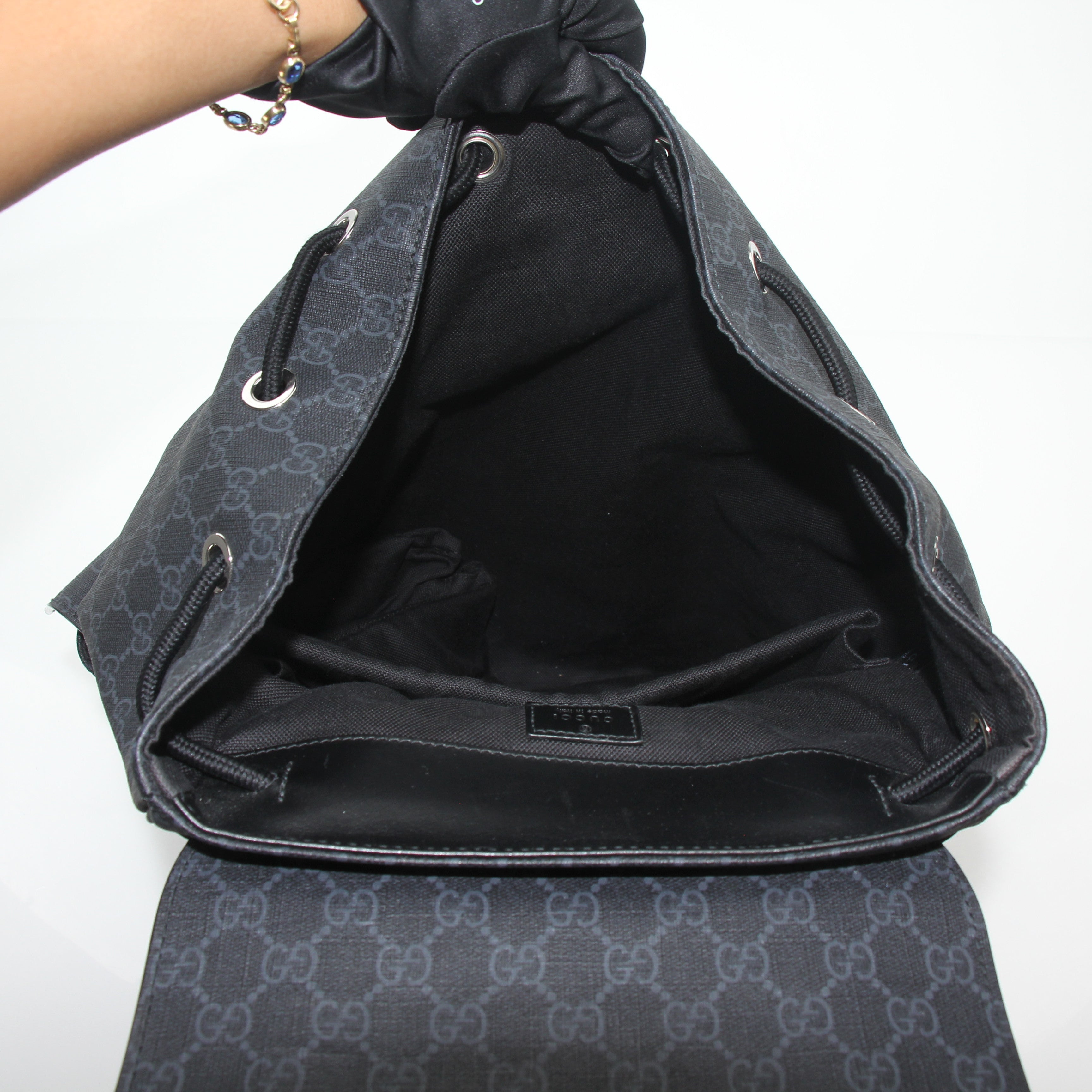 Gucci black GG Supreme Lark backpack, a stylish travel bag with sturdy straps and signature monogram pattern.