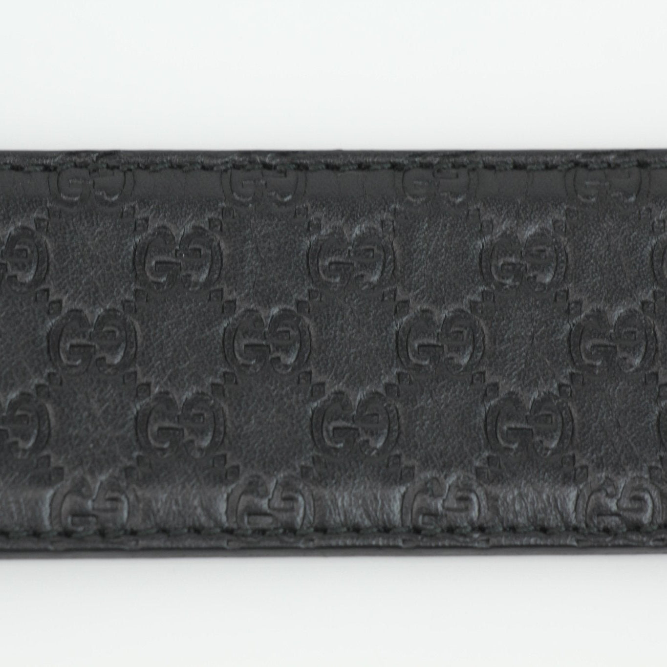 Black Gucci Guccissima belt with gold-tone buckle, featuring signature embossed pattern, designed for stylish accessories.