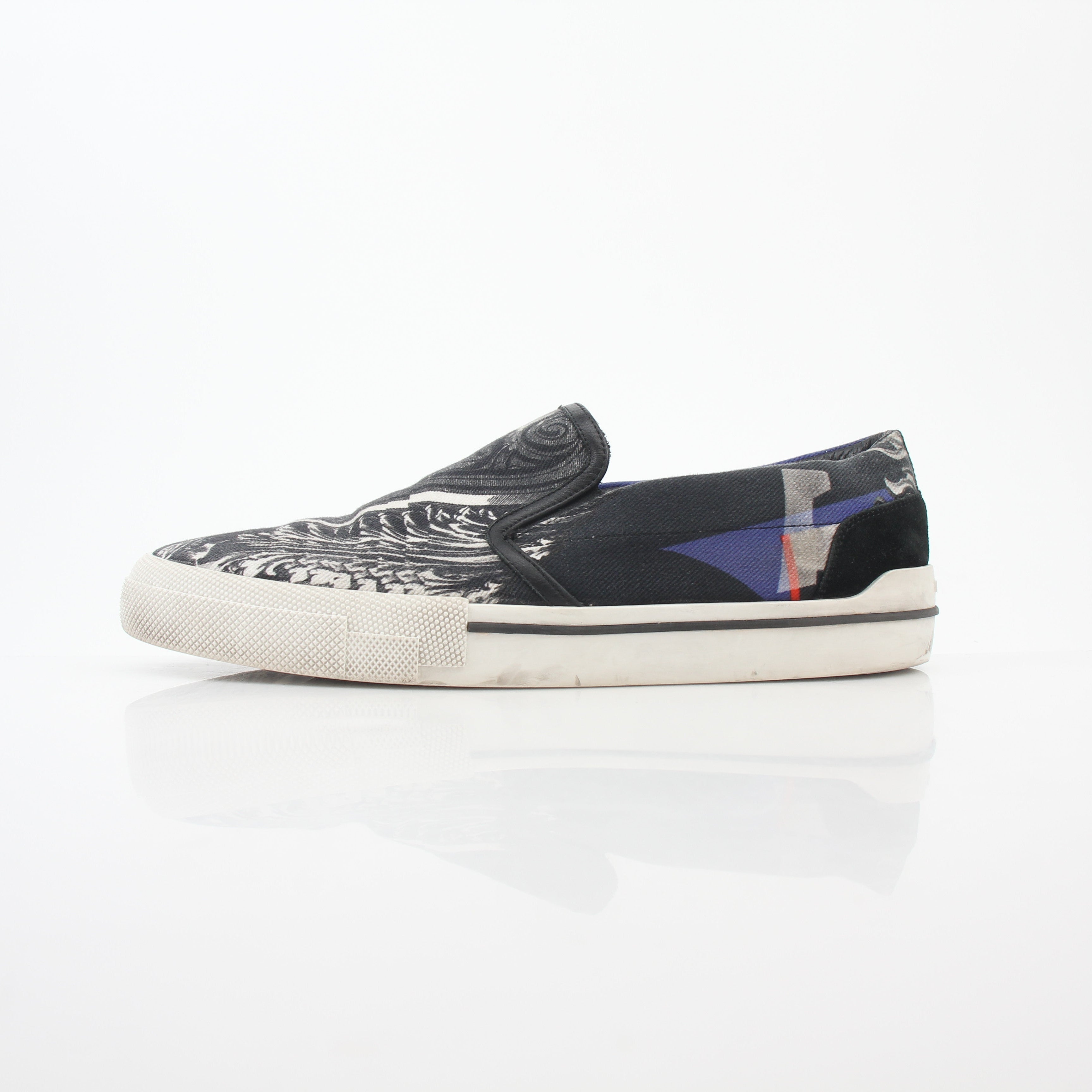 Versace men's graphic print canvas slip-on sneakers with bold design, featuring black and white artwork and casual shoe style.