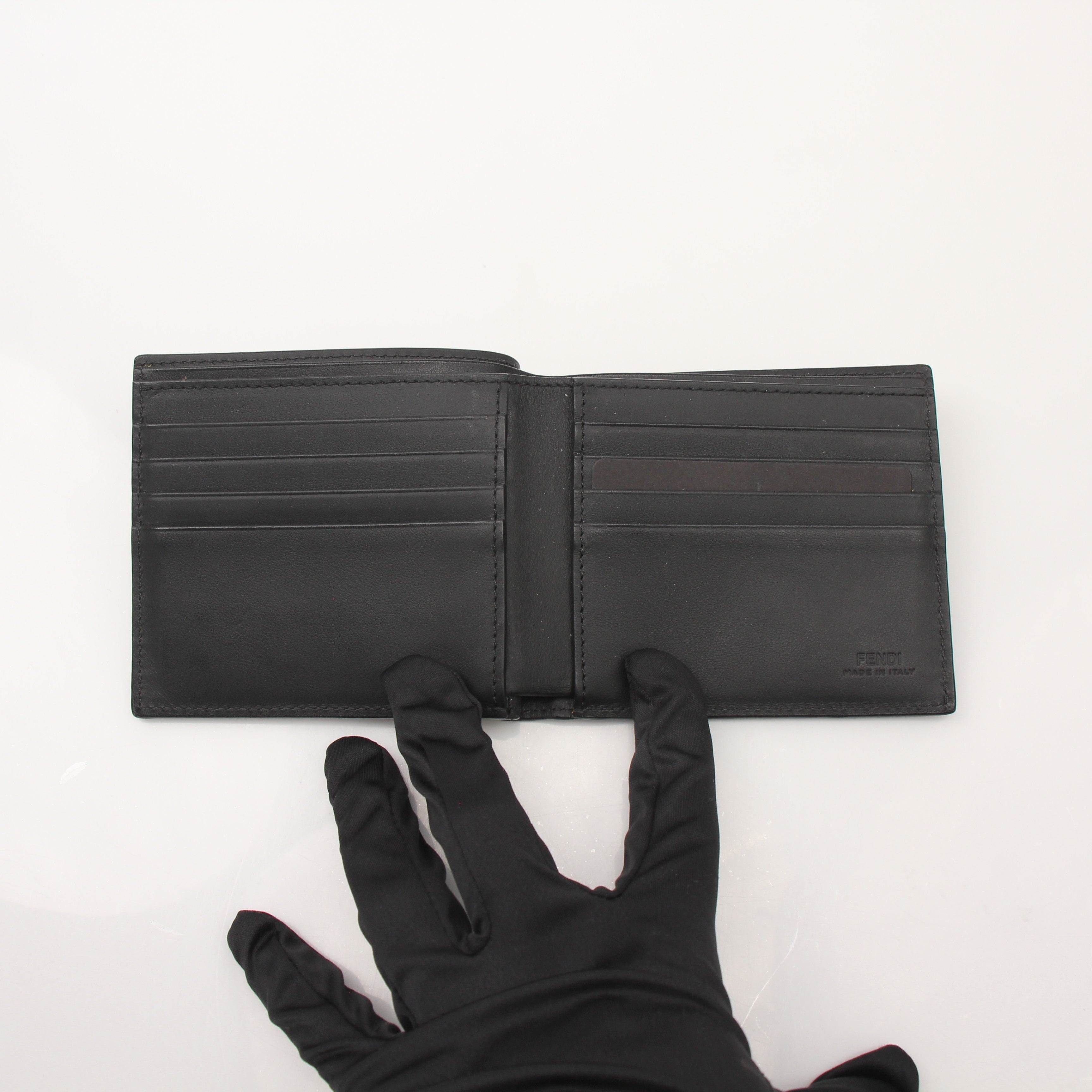 Fendi Vitello Century metal monster eyes bi-fold wallet with textured leather and gold-tone hardware, showcasing unique design details.