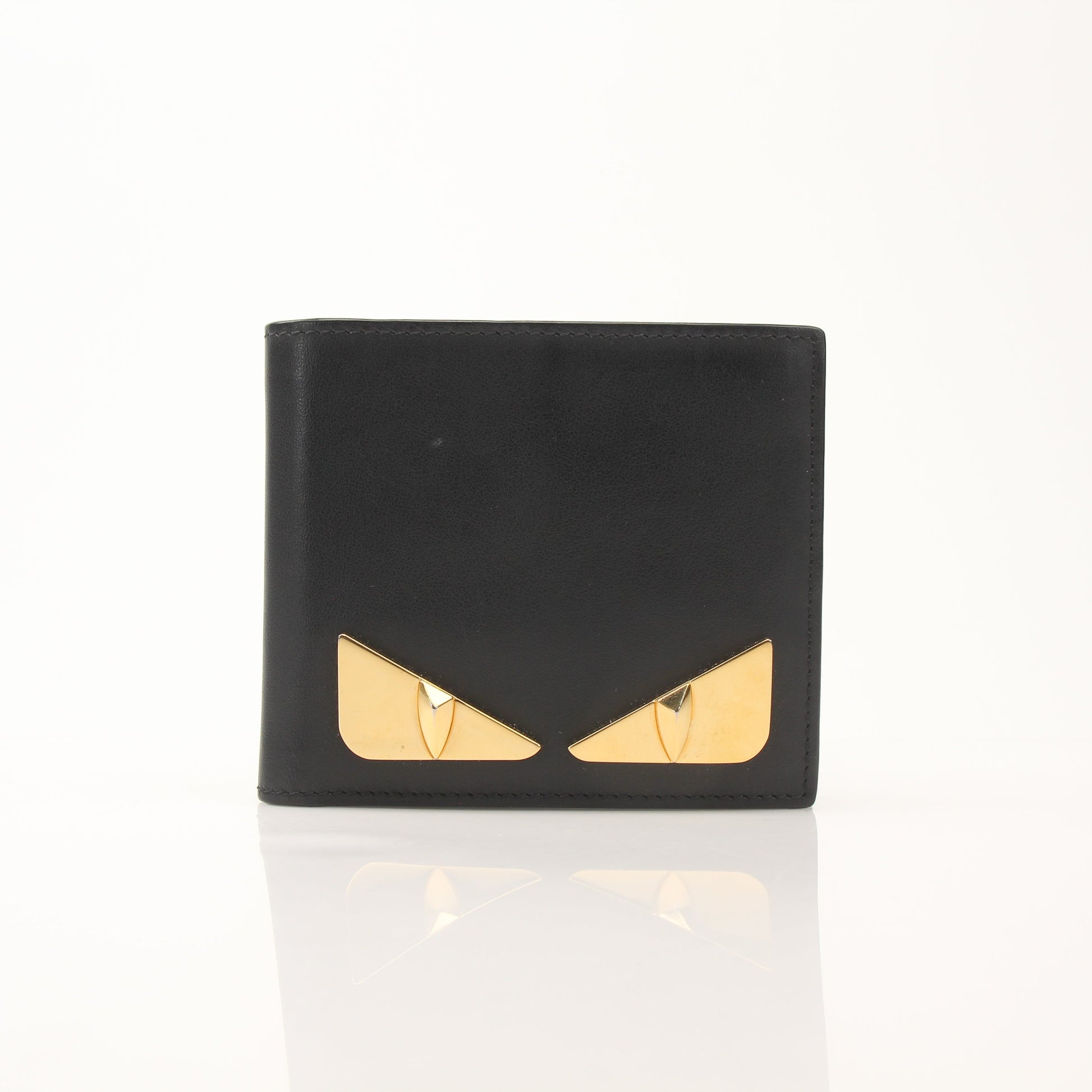 Fendi Vitello Century Metal Monster Eyes bi-fold wallet with gold accents and textured leather, featuring distinctive eye design.