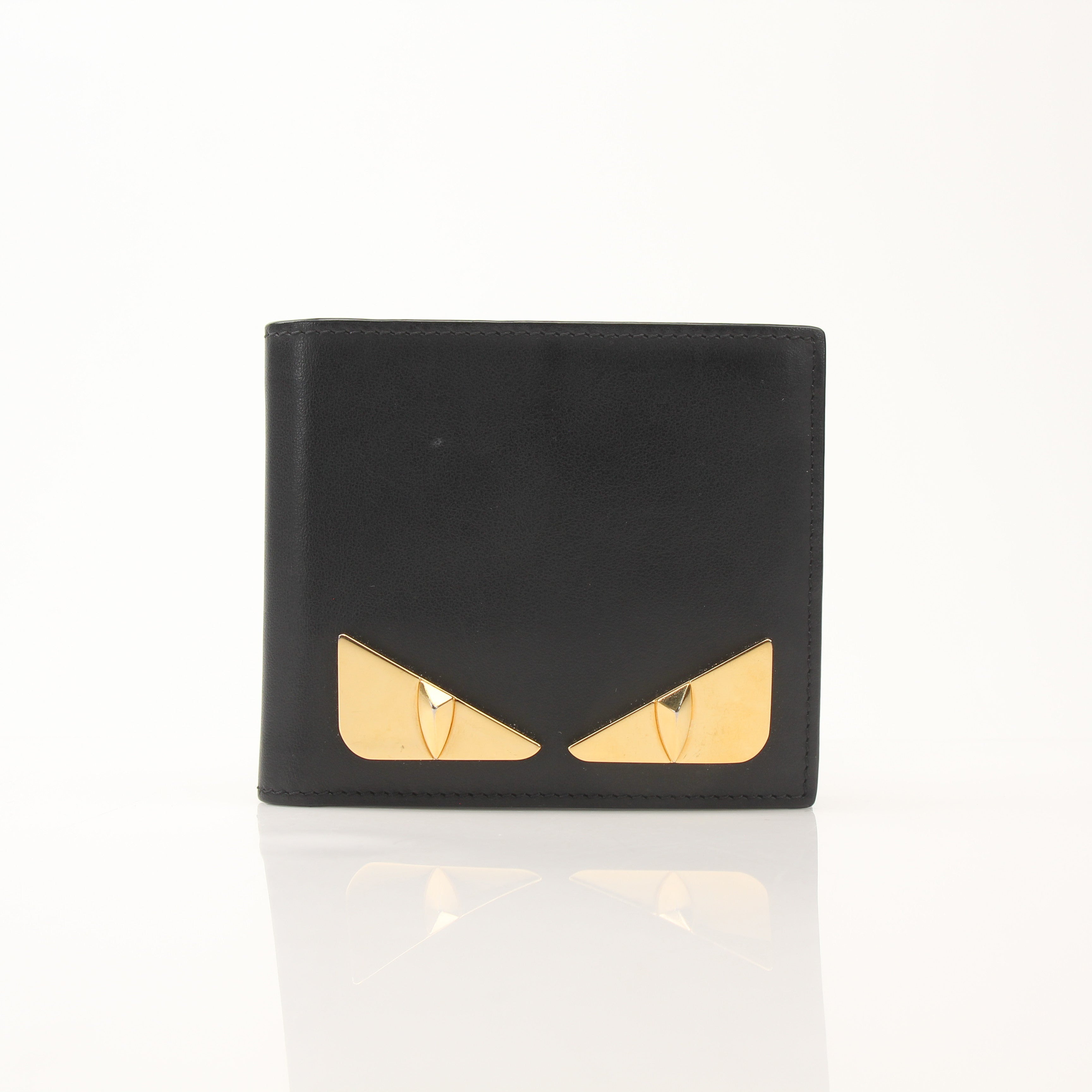 Fendi Vitello Century Metal Monster Eyes bi-fold wallet with gold accents and textured leather, featuring distinctive eye design.