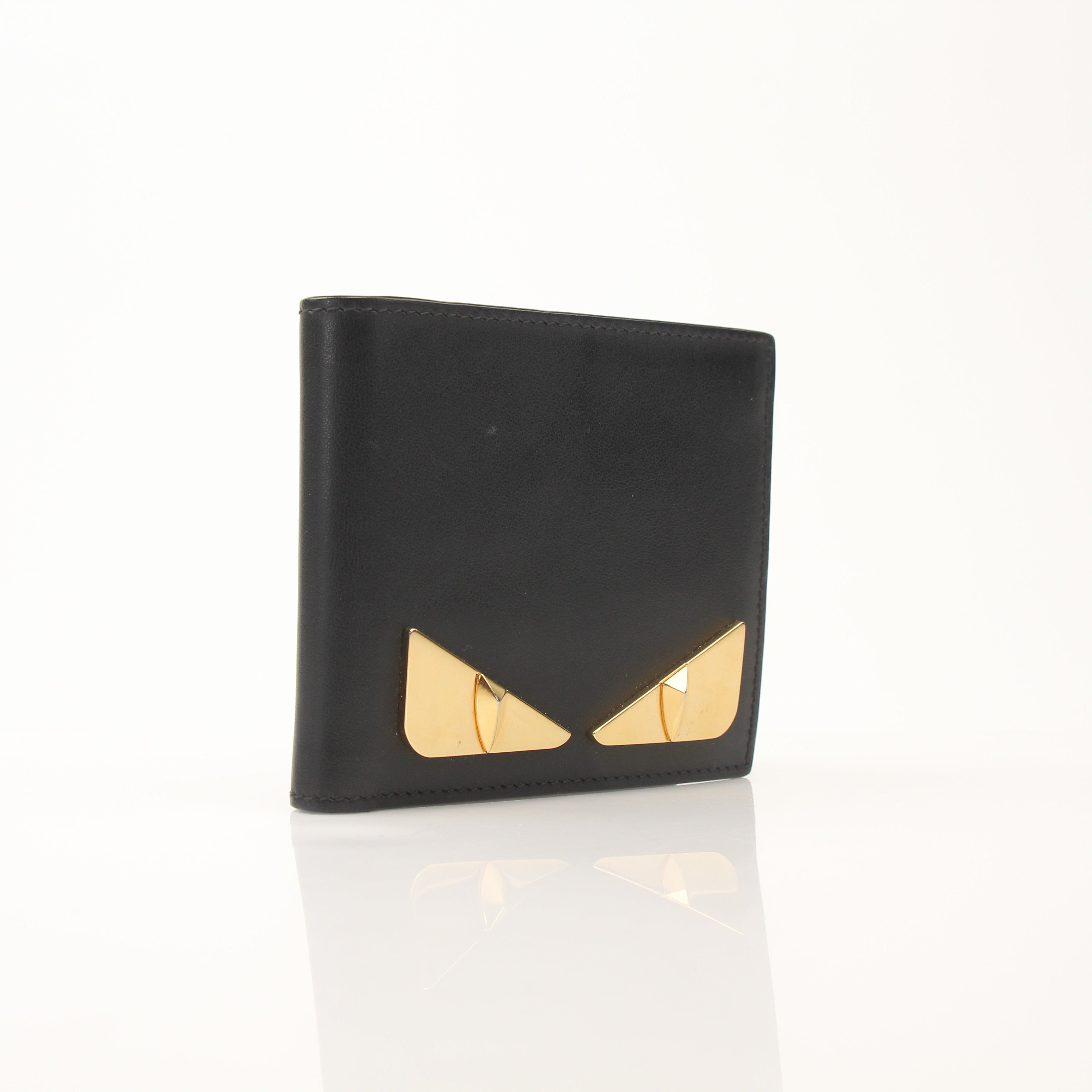 Fendi Vitello Century metal monster eyes bi-fold wallet with gold accents and textured leather detailing.