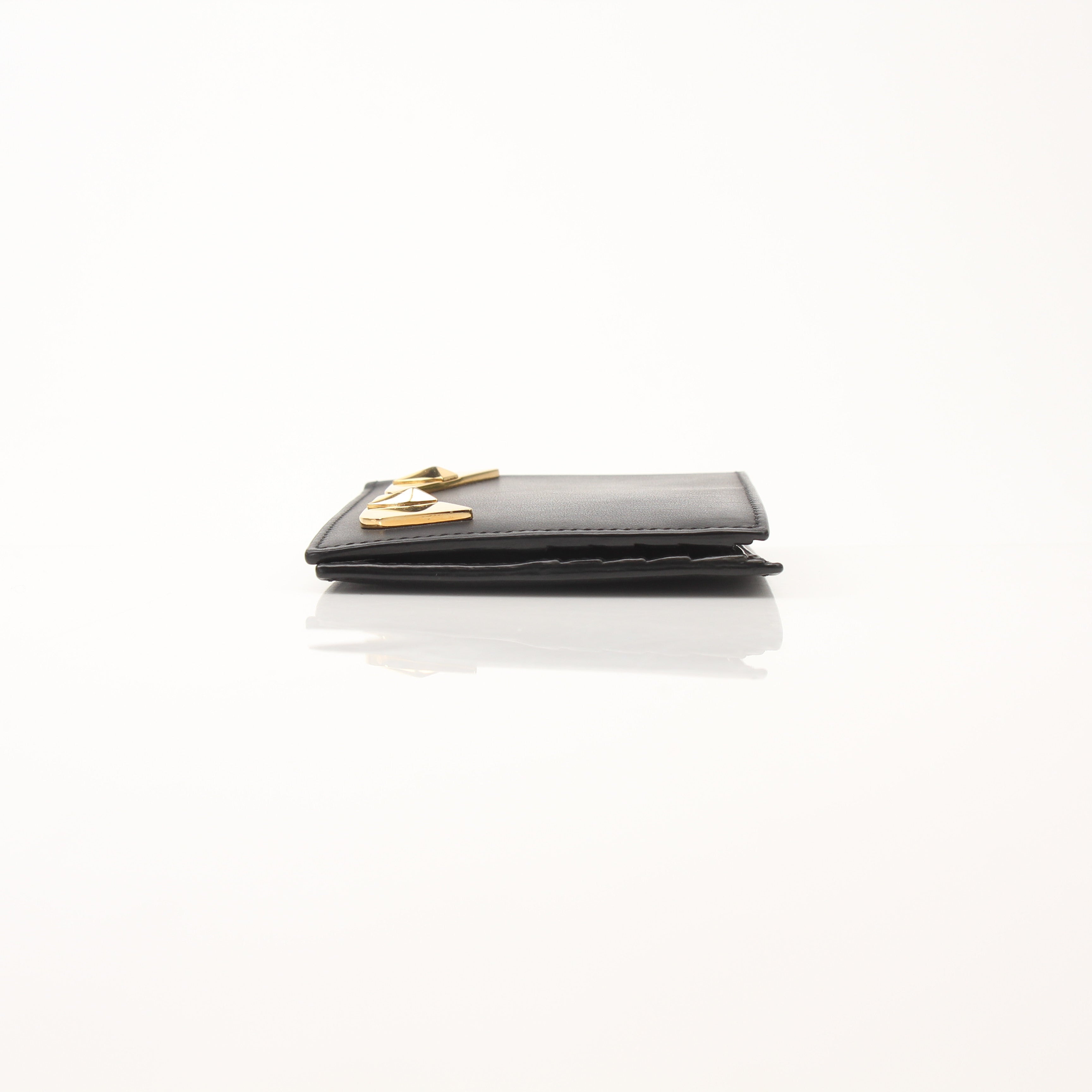 Fendi Vitello Century metal-eyed bi-fold wallet with gold accents and textured leather, open to show card slots and interior details.