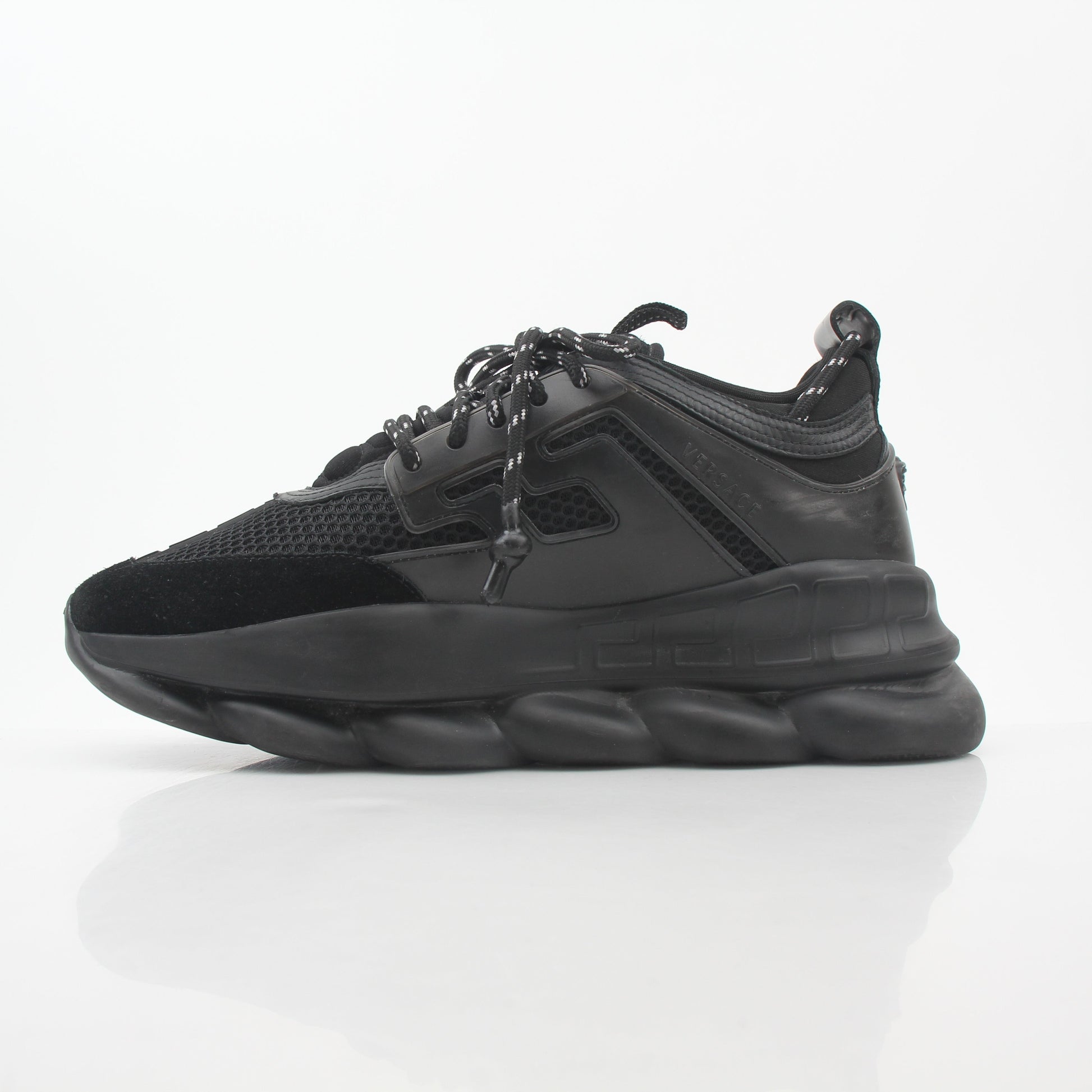 Black Chain Reaction sneakers by Versace featuring gold accents and stylish design, displayed on a white background.