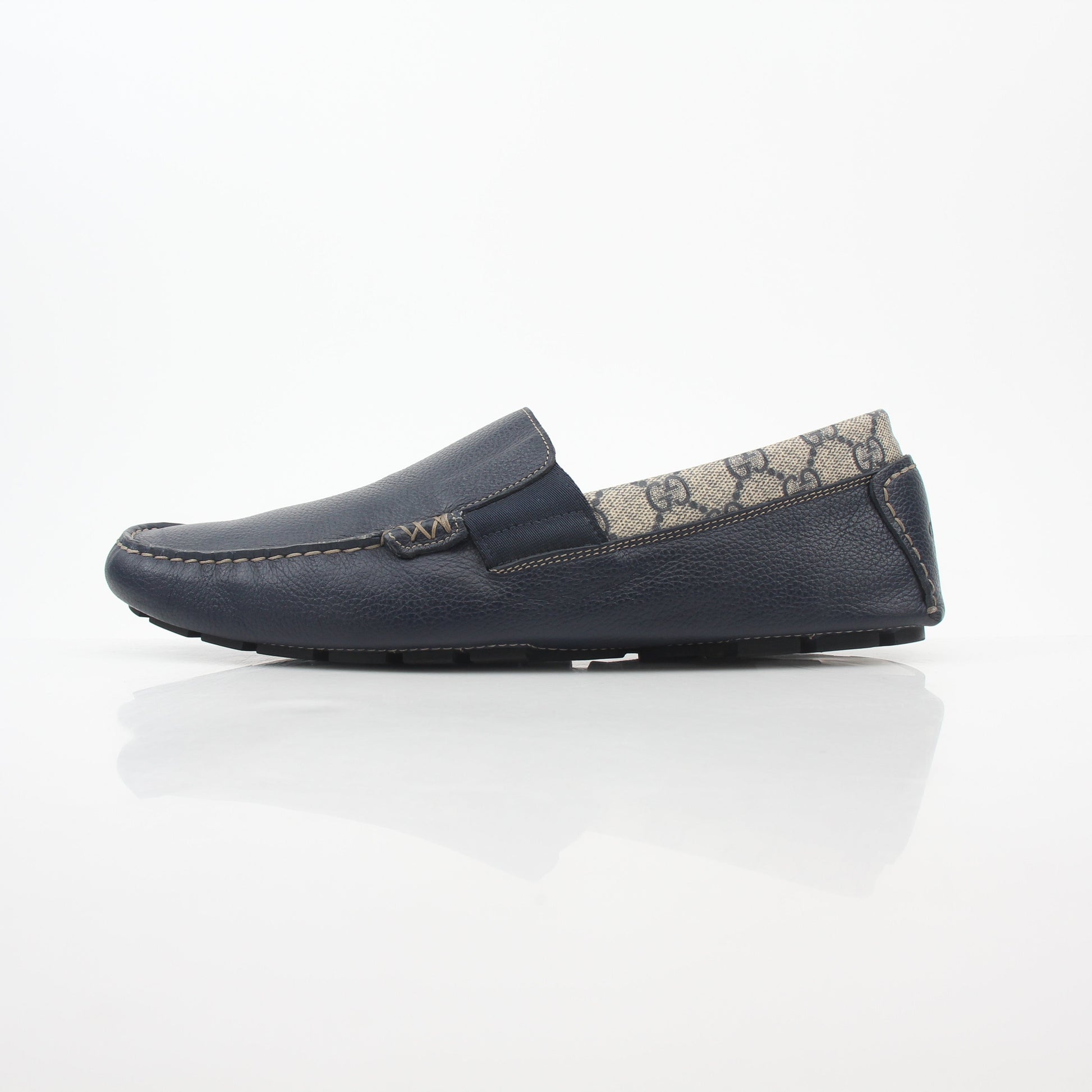Gucci navy GG Supreme leather driver loafers with classic design and slip-on style, featuring gold accents and a comfortable sole.