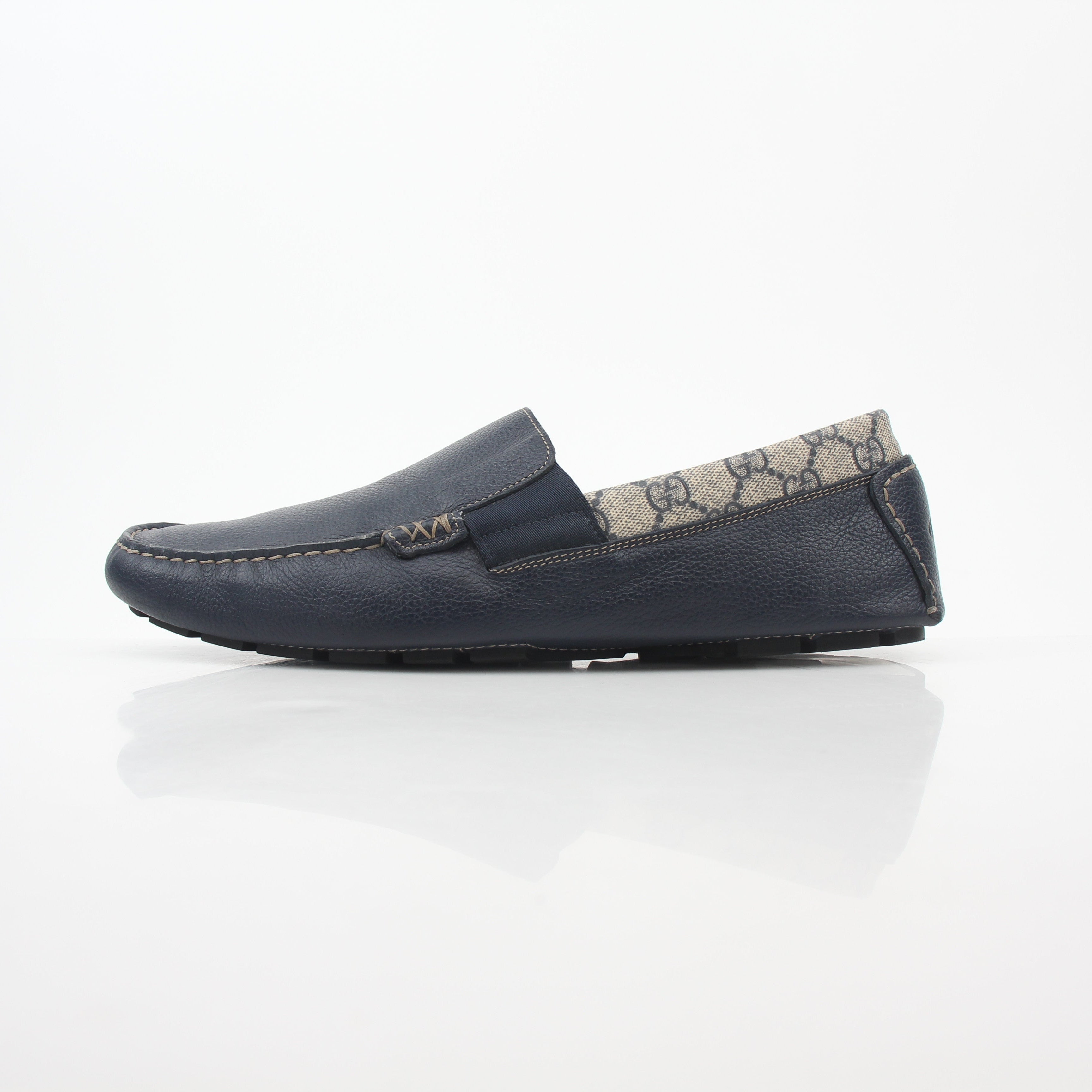 Gucci navy GG Supreme leather driver loafers with classic design and slip-on style, featuring gold accents and a comfortable sole.