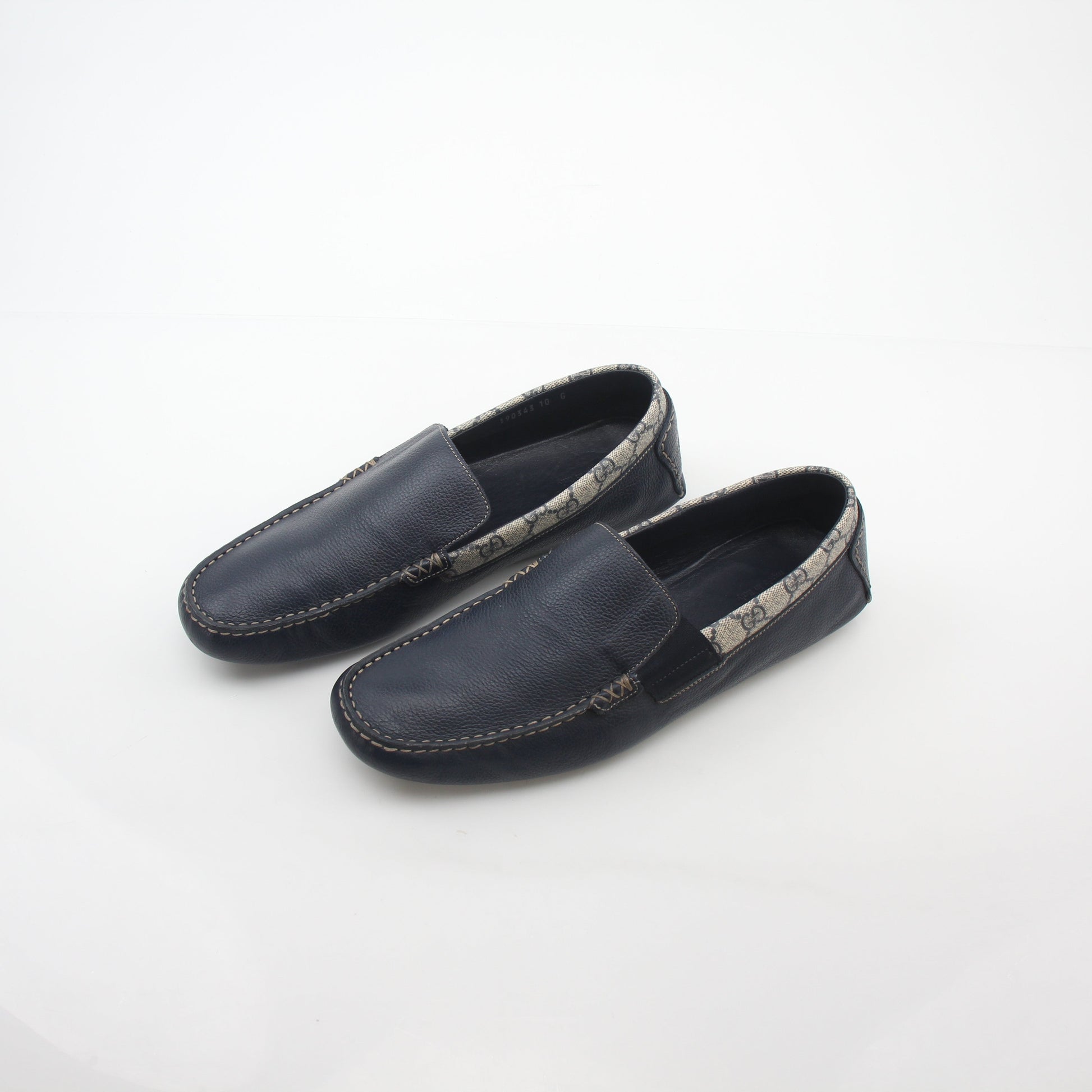Gucci navy GG Supreme leather driver loafers with slip-on design and low heel, showcased on a neutral background.