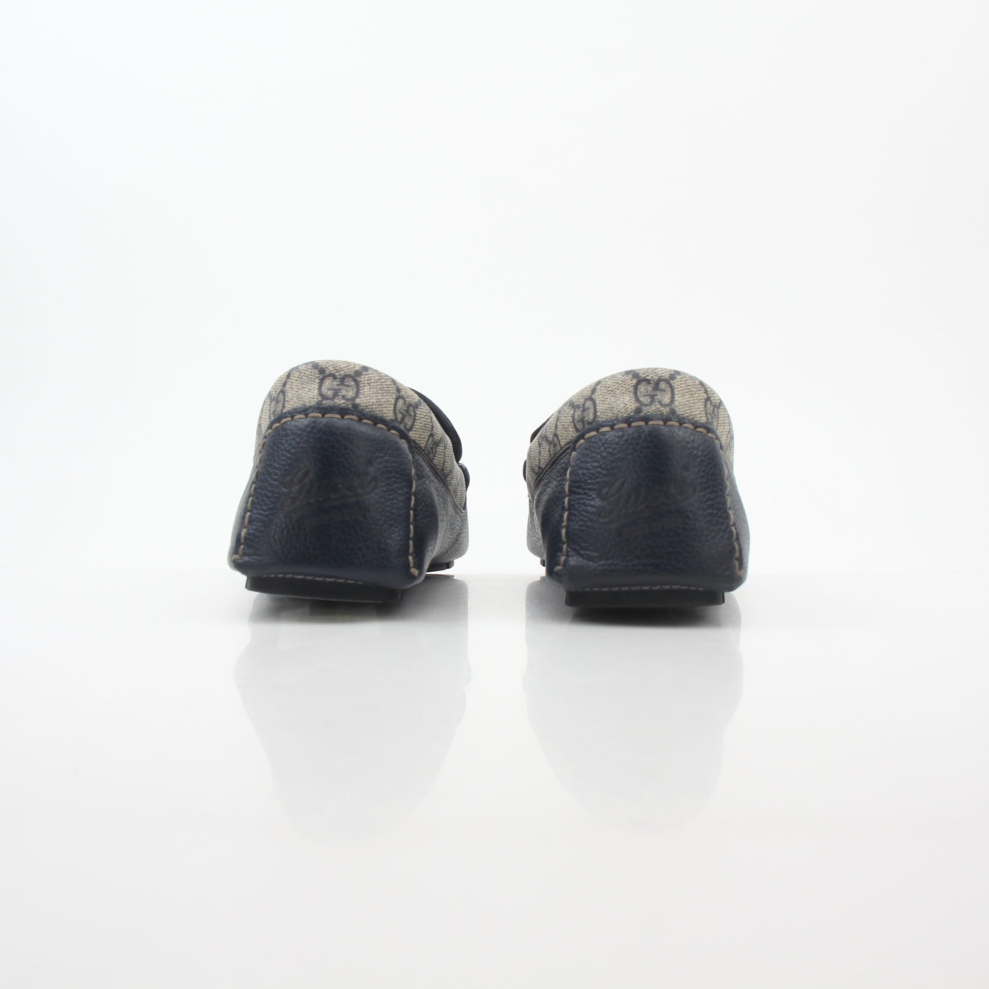 Gucci Navy GG Supreme leather driver loafers with gold accents, showcasing sleek footwear design and premium craftsmanship.