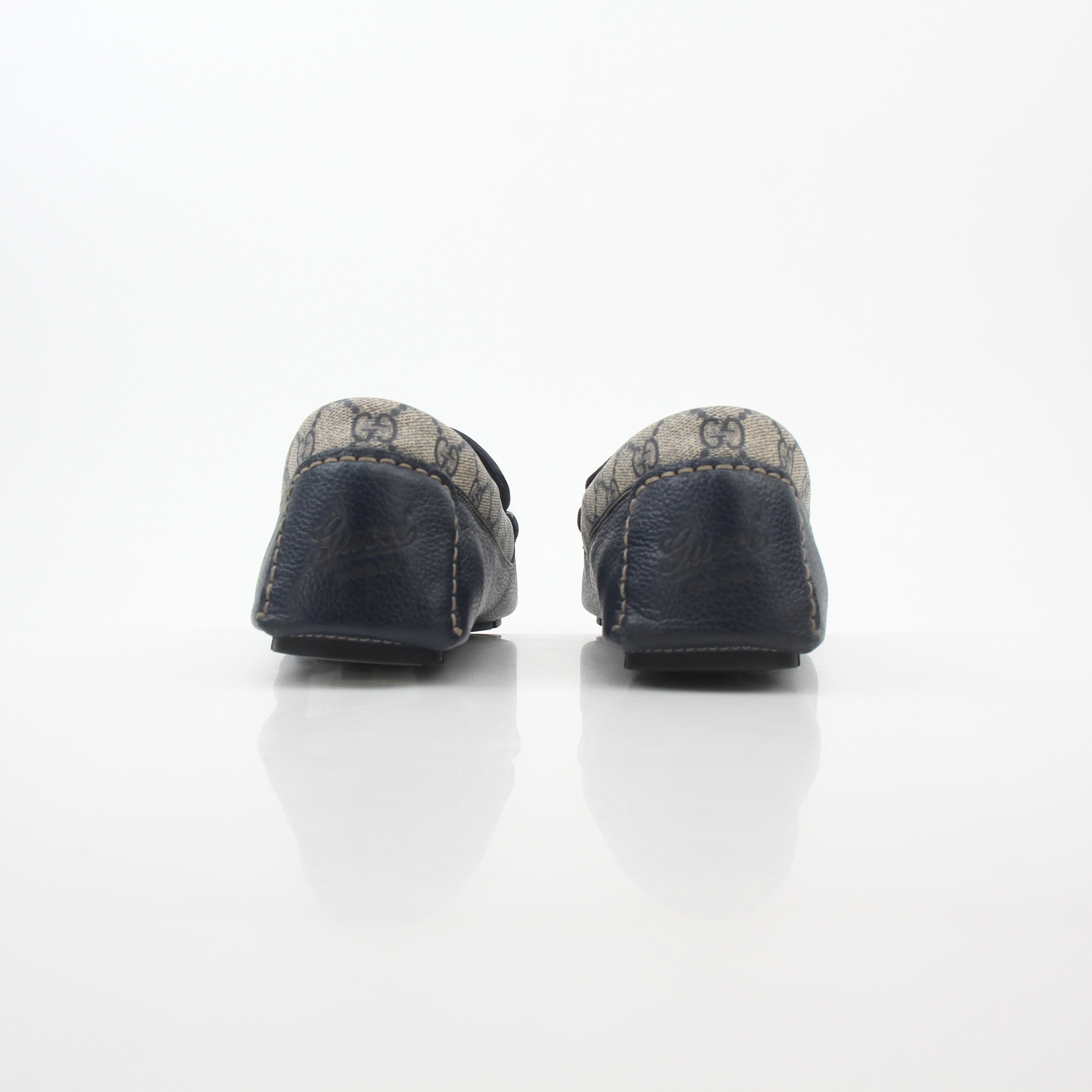 Gucci Navy GG Supreme leather driver loafers with gold accents, showcasing sleek footwear design and premium craftsmanship.