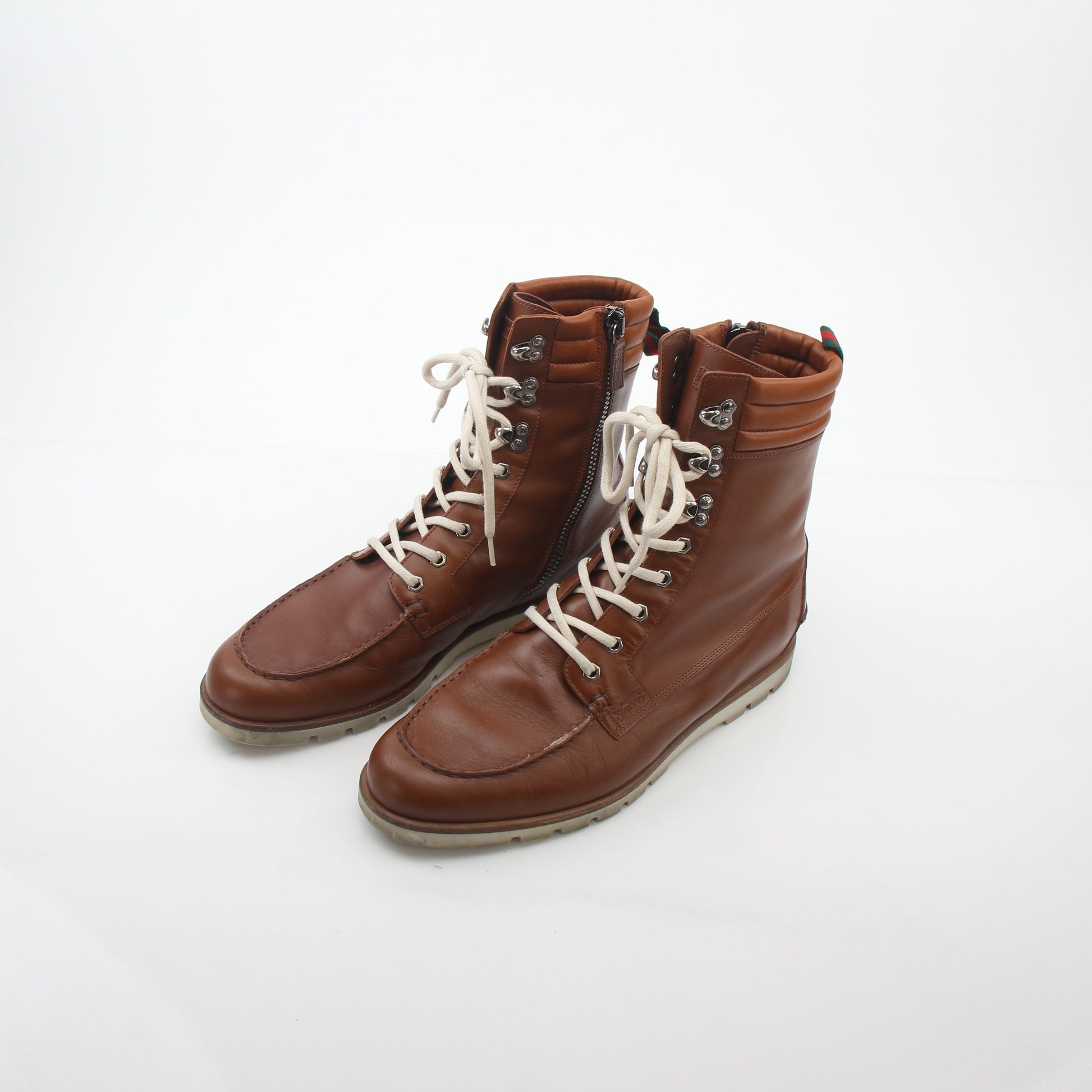 Gucci brown leather web accent hiking boots with rugged soles and lace-up design, showcasing luxury footwear craftsmanship.