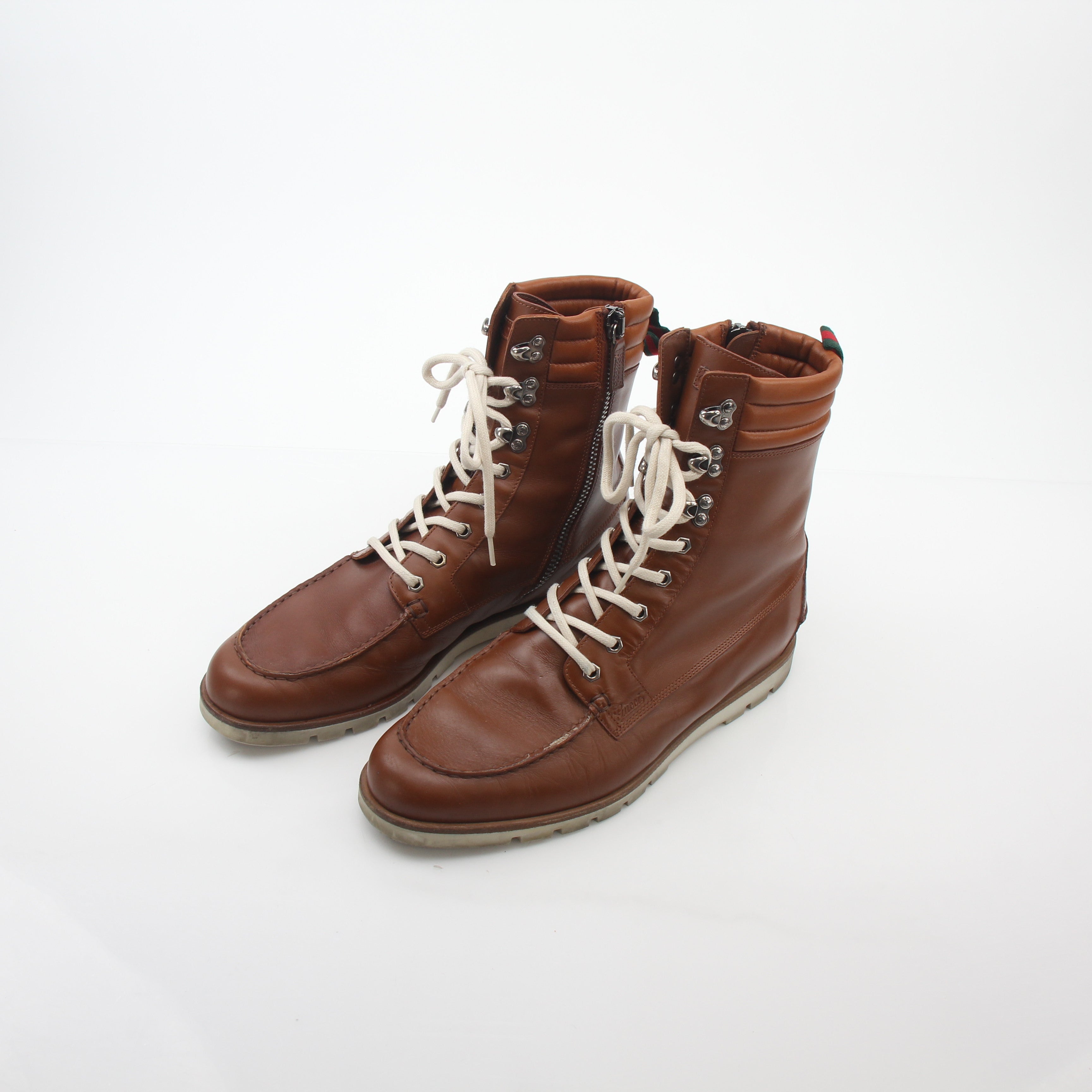 Gucci brown leather web accent hiking boots with rugged soles and lace-up design, showcasing luxury footwear craftsmanship.