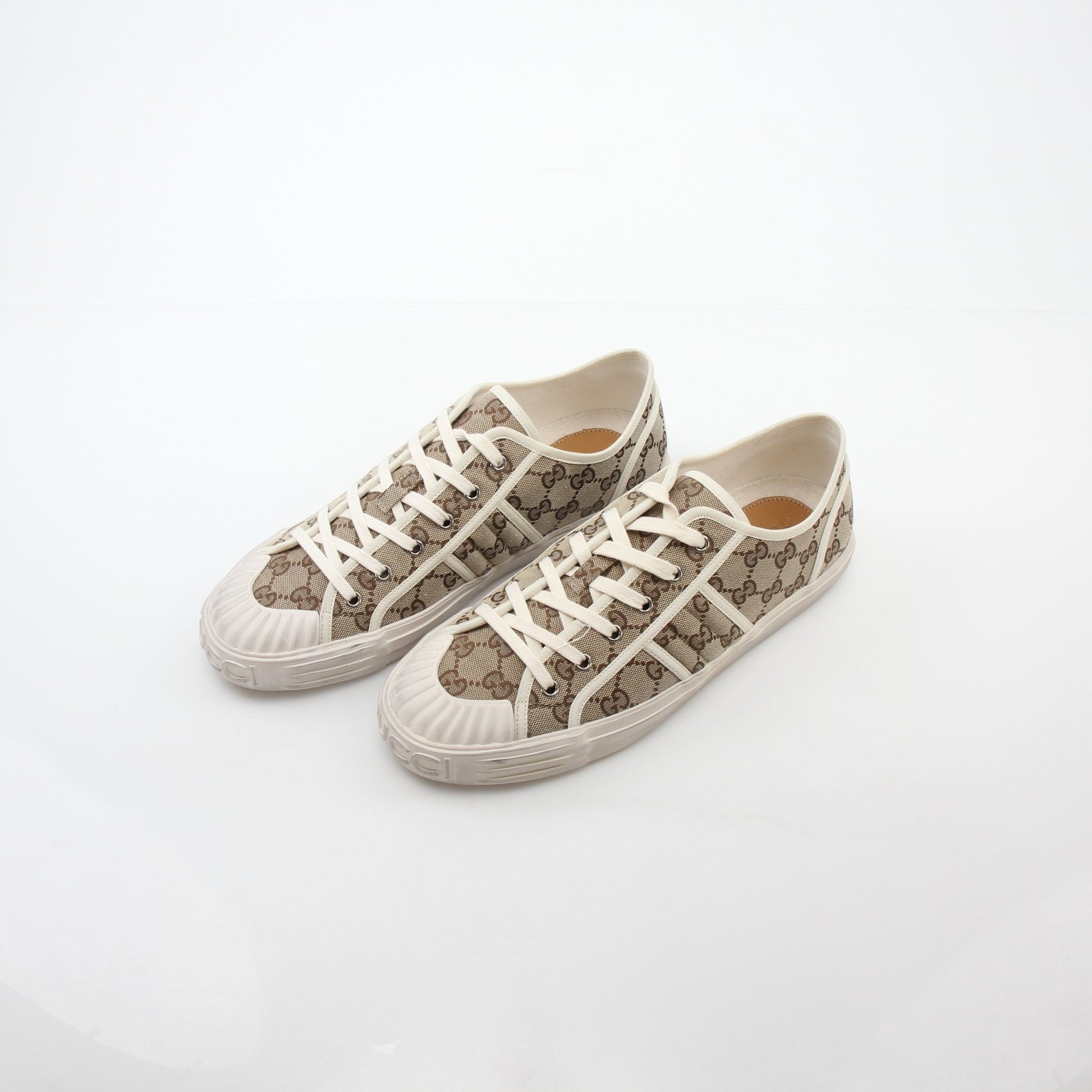 Gold & Beyond Gucci GG Supreme sneakers featuring classic logo print, white rubber soles, and stylish casual shoe design.