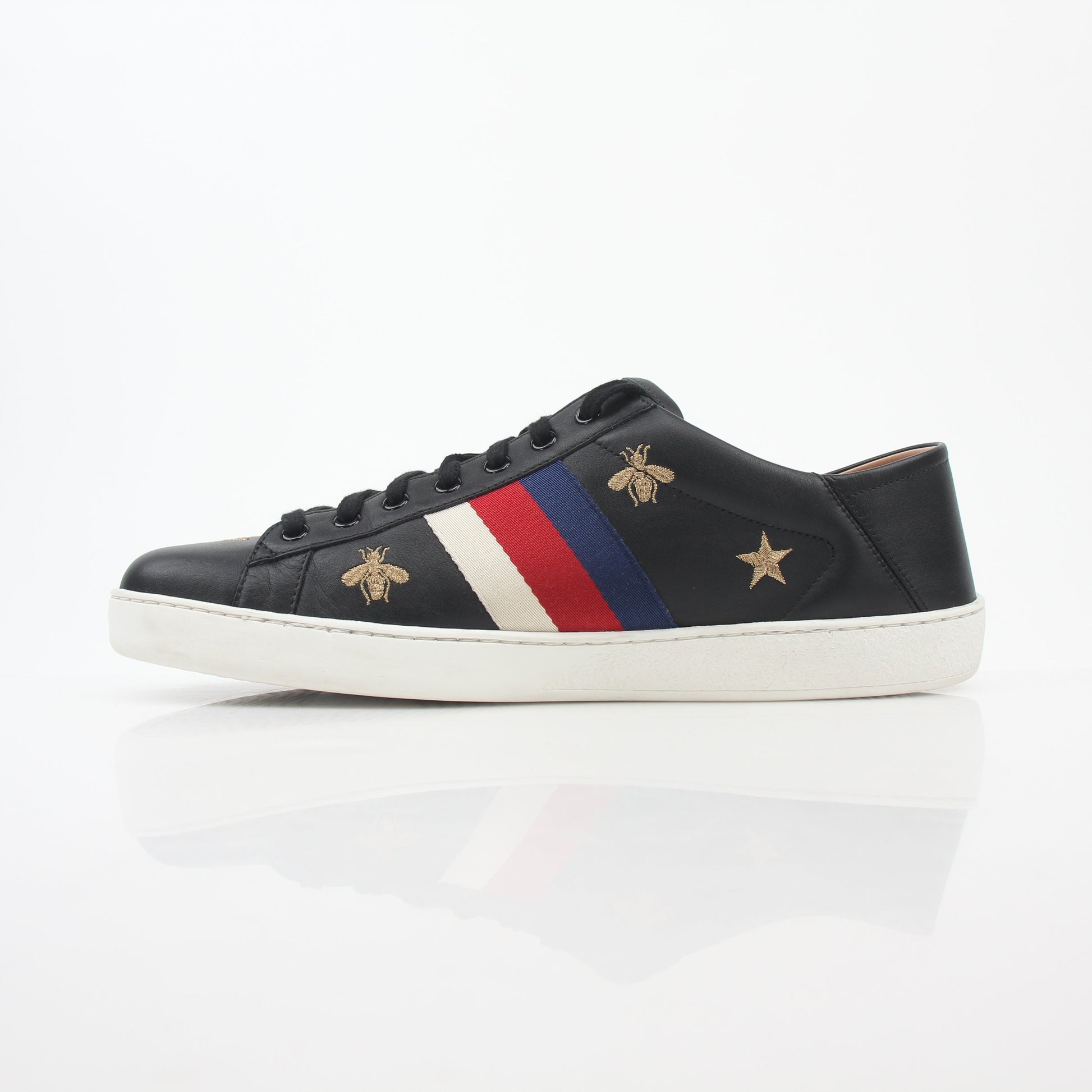 Gucci black embroidered Ace Web low-top sneakers with white soles and signature design, displayed on a plain background.